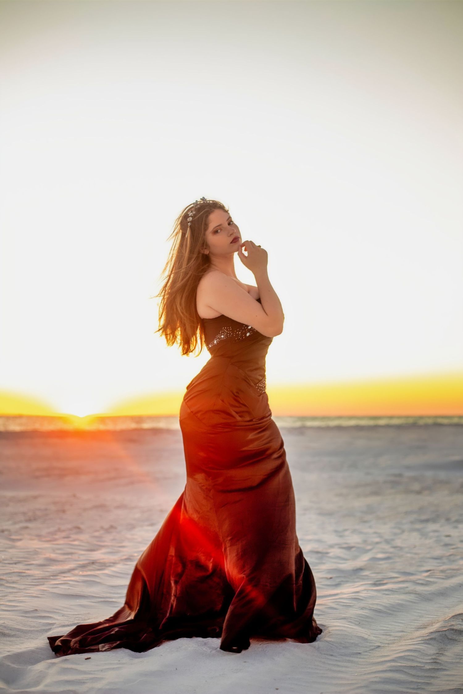 Sunset beach photography session featuring a dark dress against golden light on white sand.