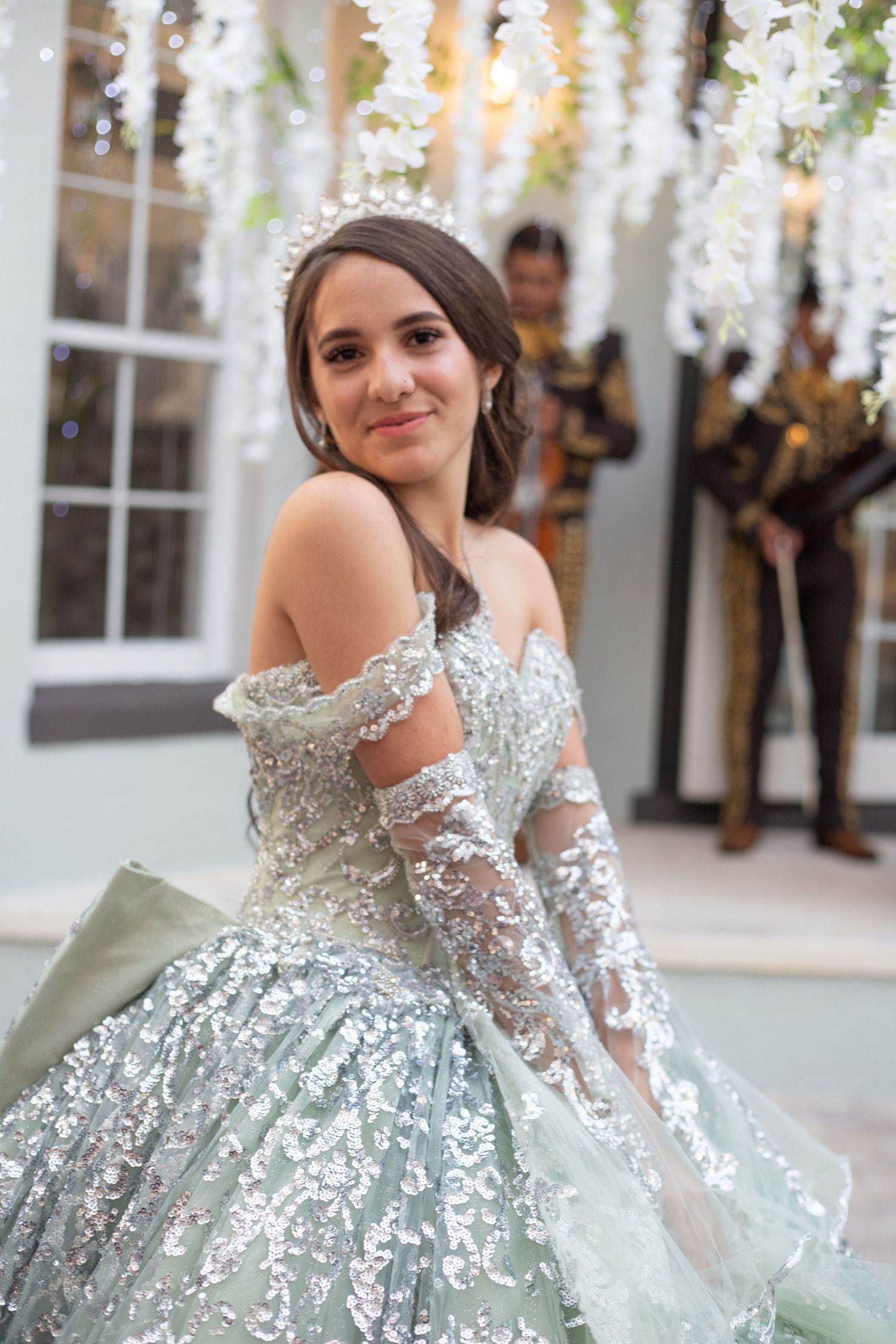 Elegant mint green sequined ballgown with delicate lace details under white floral decorations.