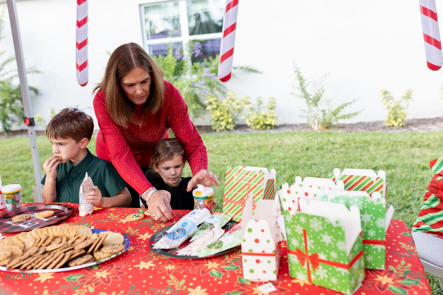 Outdoor holiday gathering with red and white striped decorations and festive table settings.