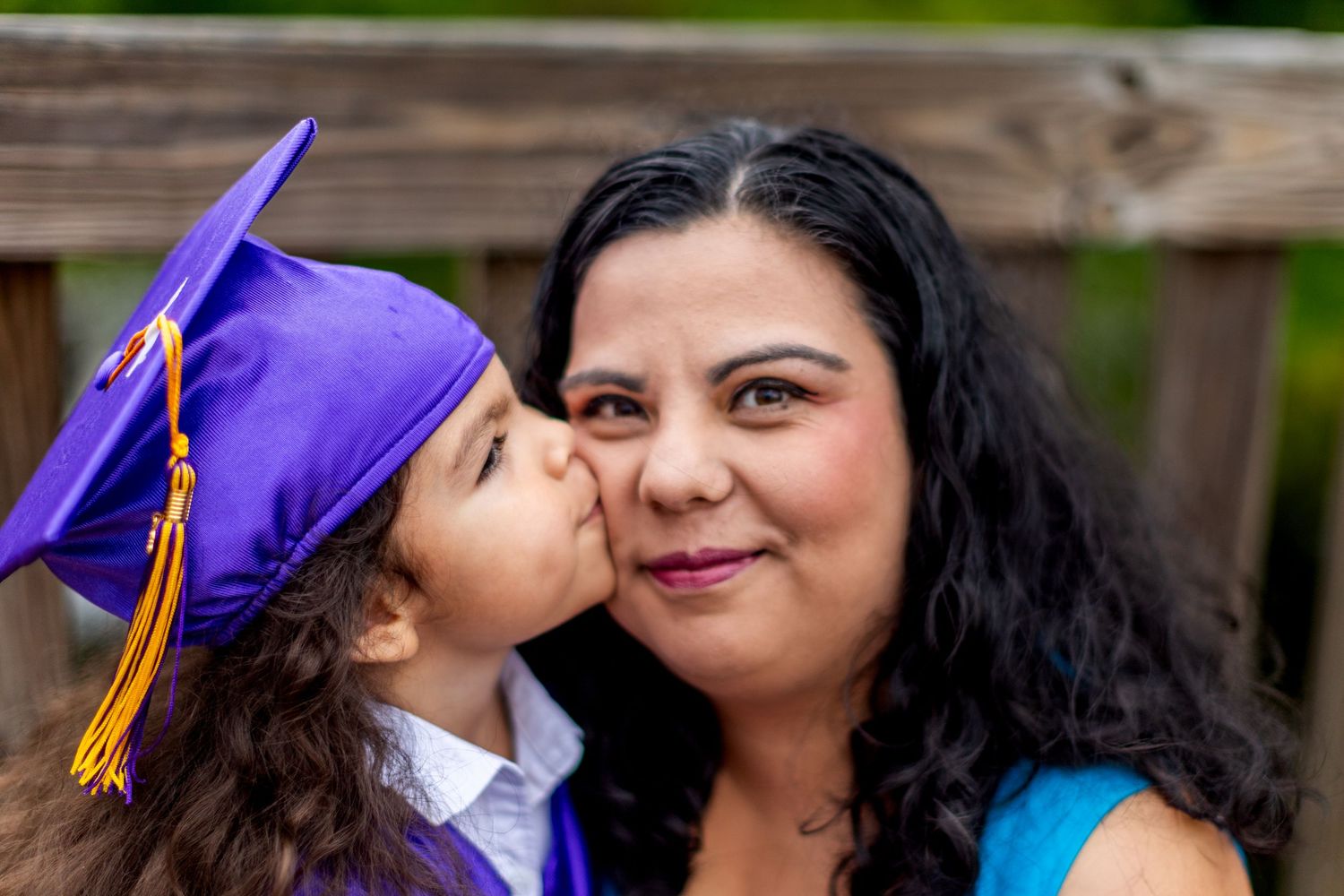 Heartwarming graduation photo session on wooden deck with matching purple and blue outfits.