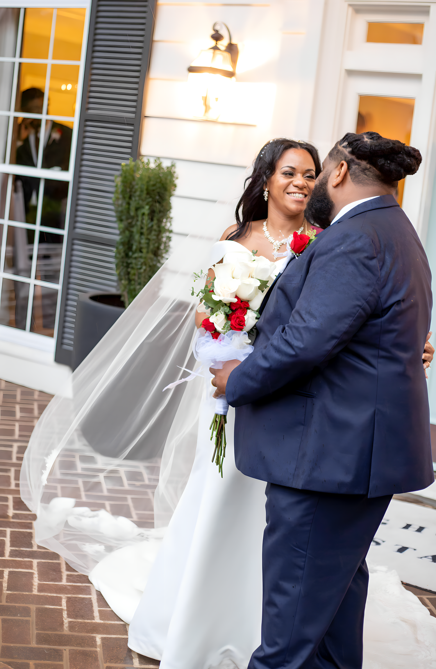 A romantic moment captured between newlyweds outside with a flowing white veil.