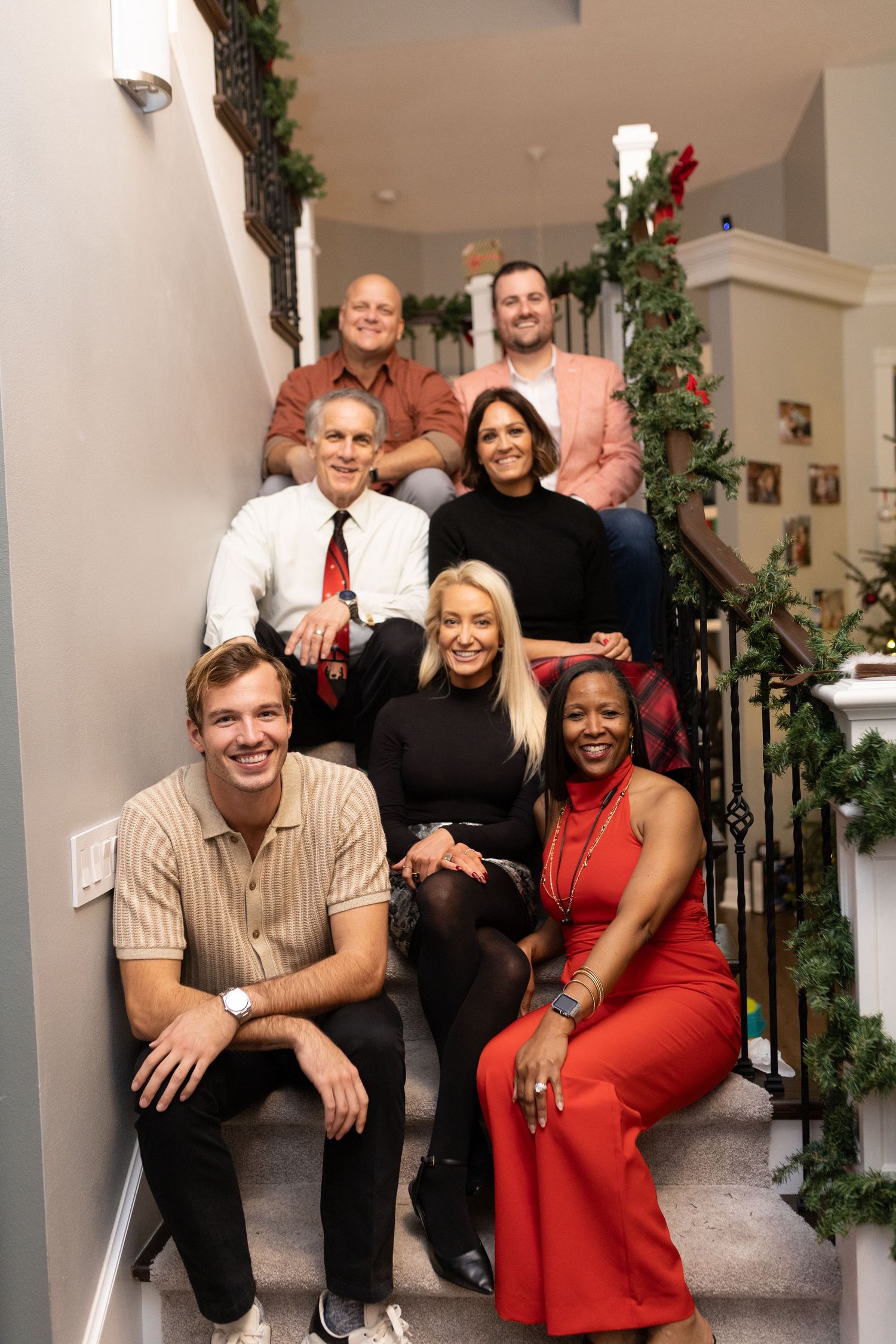 People gathered on decorated stairs for holiday photos with Santa Claus.