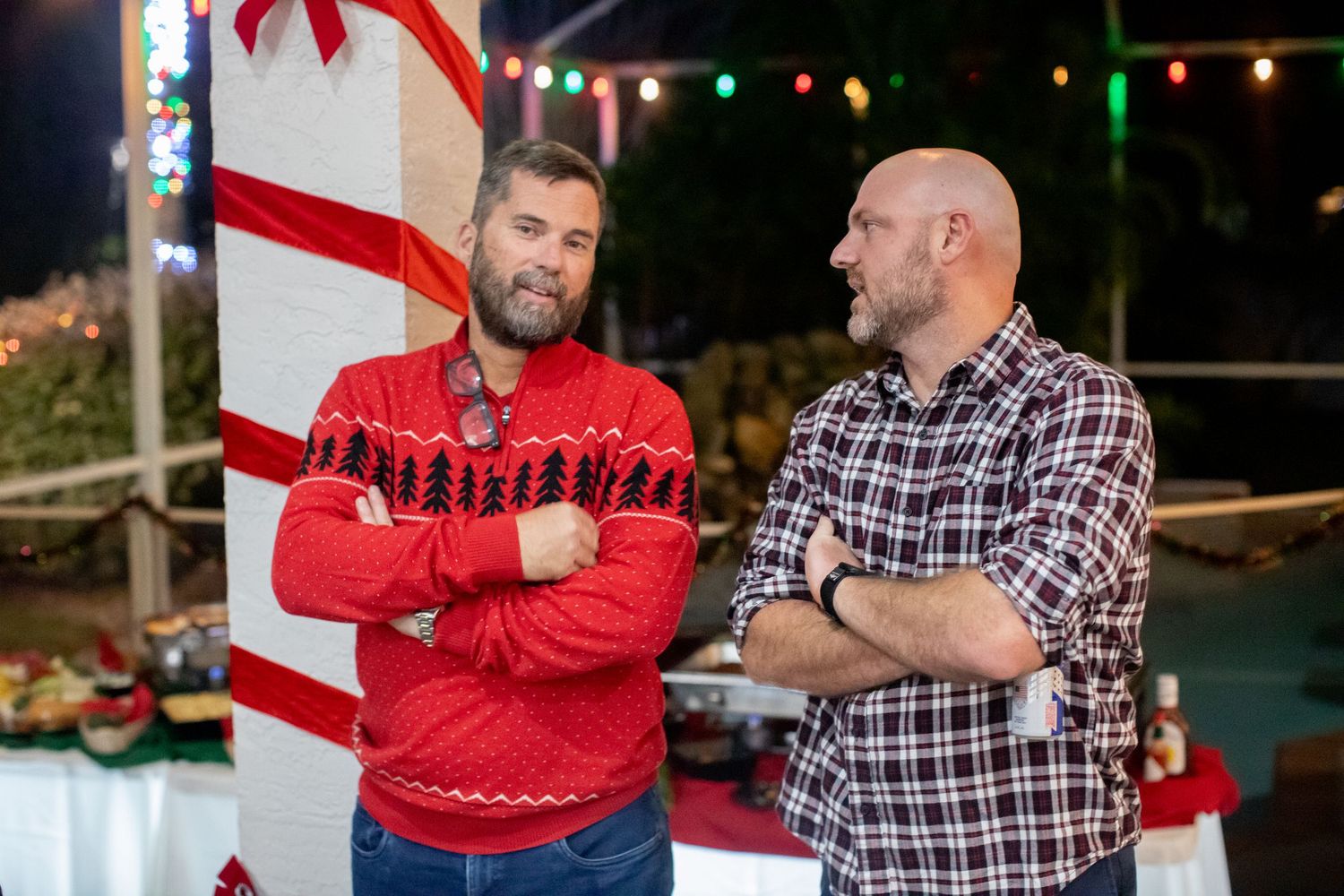 People celebrating at a holiday party with red and white candy cane decorations visible.