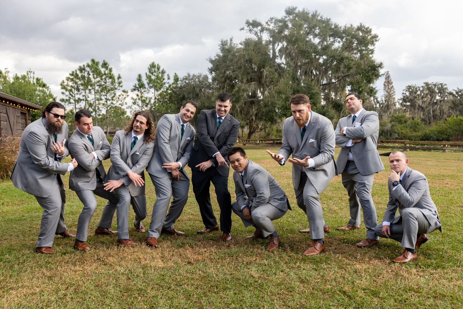 Groomsmen in gray suits showing off colorful socks in fun group photo pose.