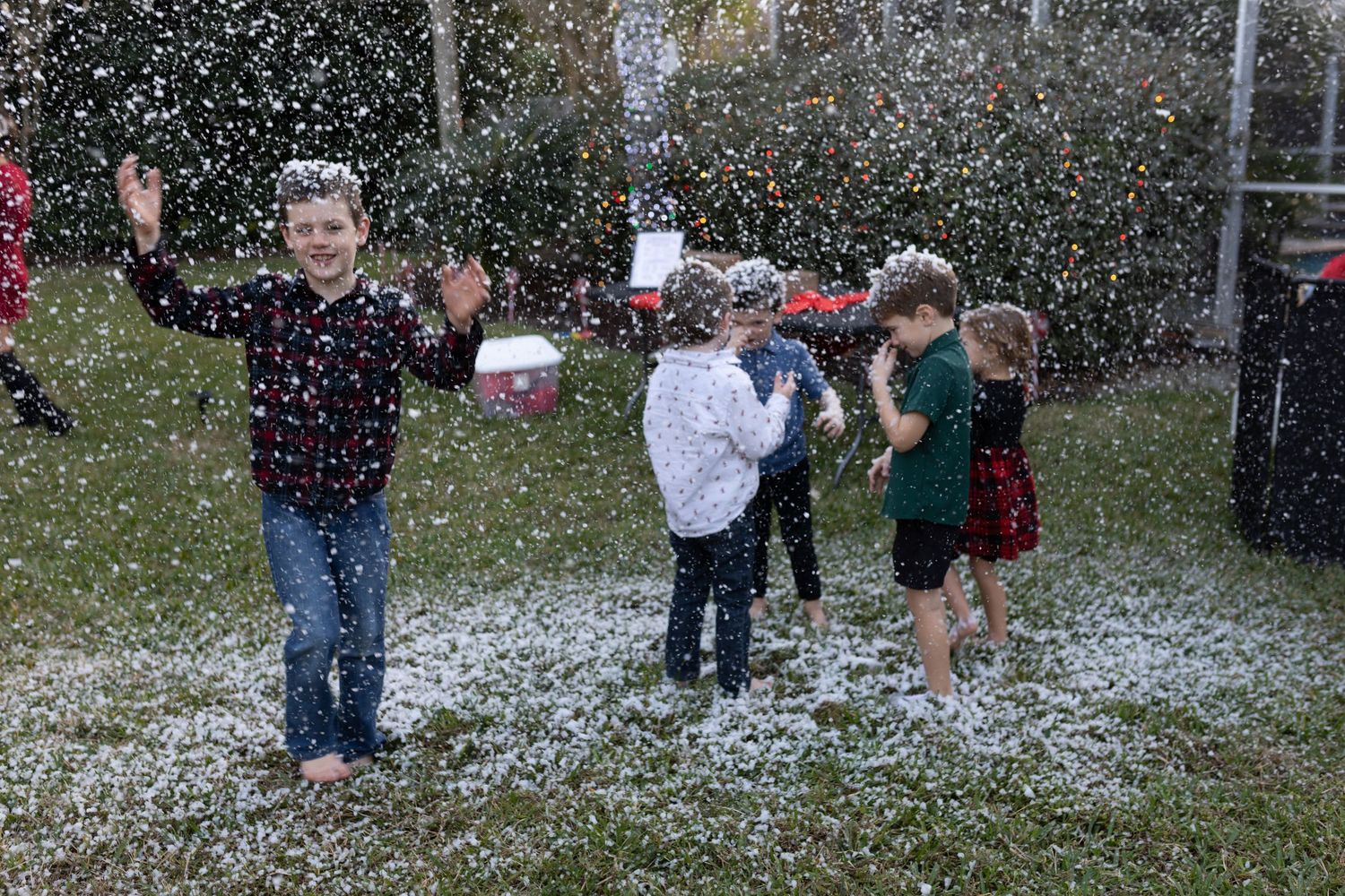 People playing in artificial snow during an outdoor celebration.