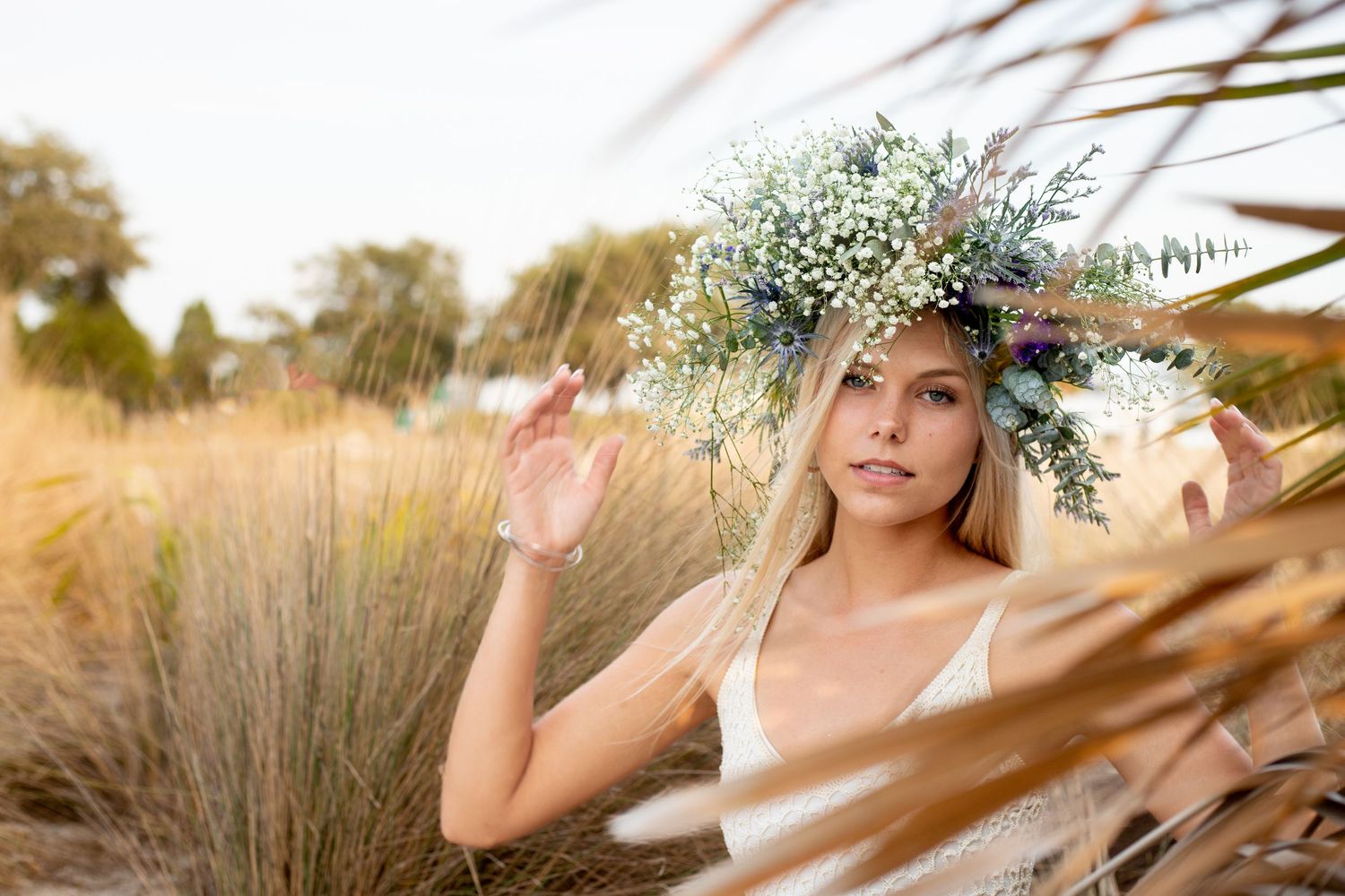 Bohemian style portrait with floral crown against natural grass backdrop.