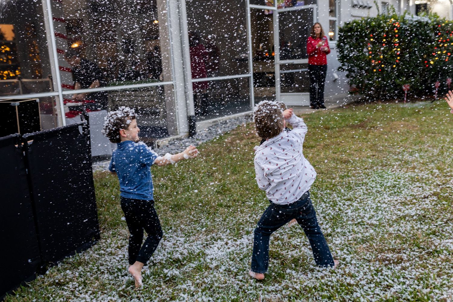 People playing in falling artificial snow during outdoor winter celebration.