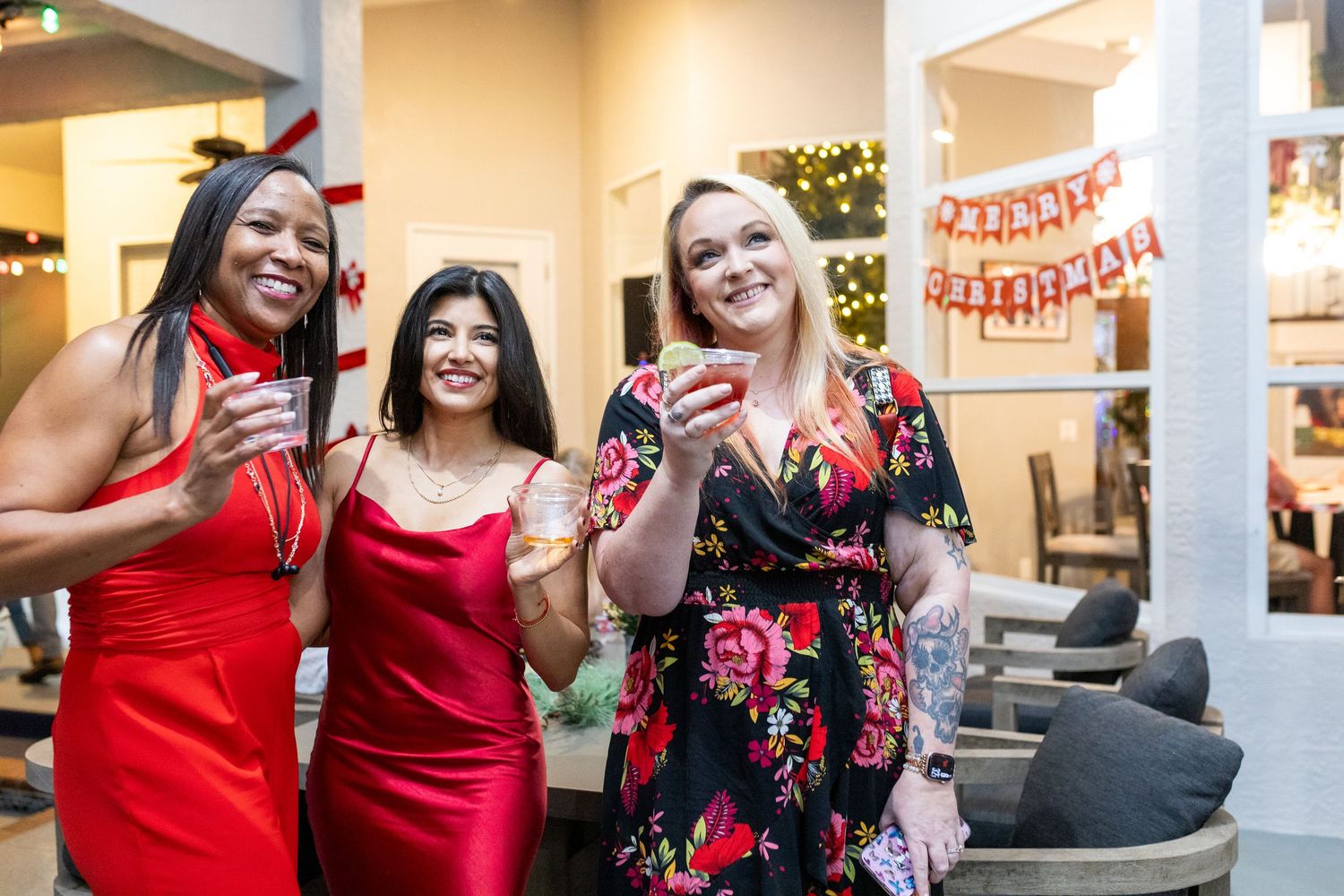 Women celebrating and dancing at a festive holiday gathering in an indoor venue.