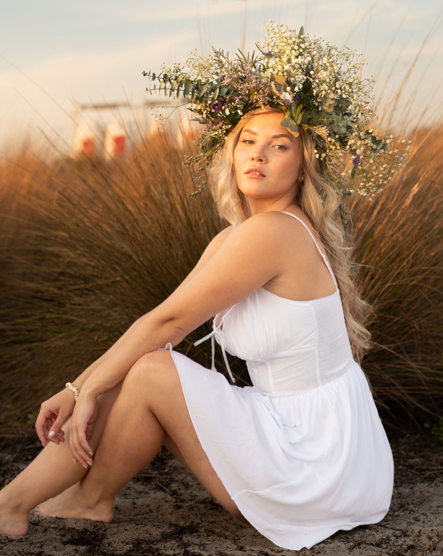 Dreamy beach portrait in a flowing white dress with natural grasses at sunset.