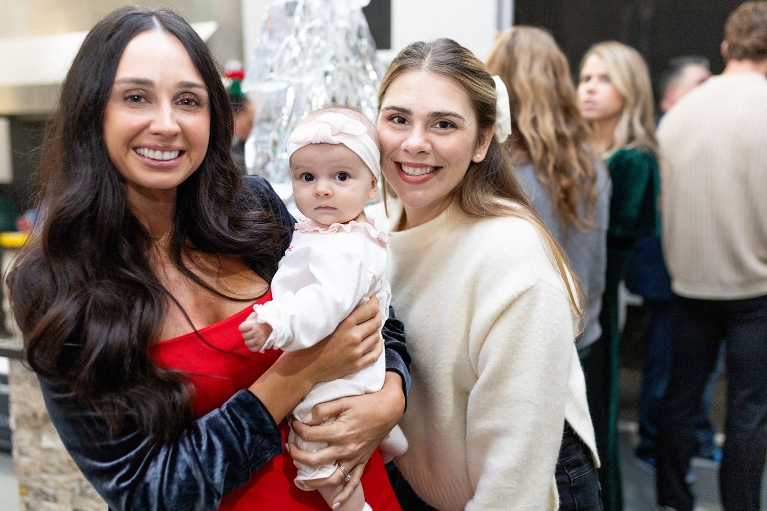 People gathered together at a holiday celebration with festive decor and string lights.