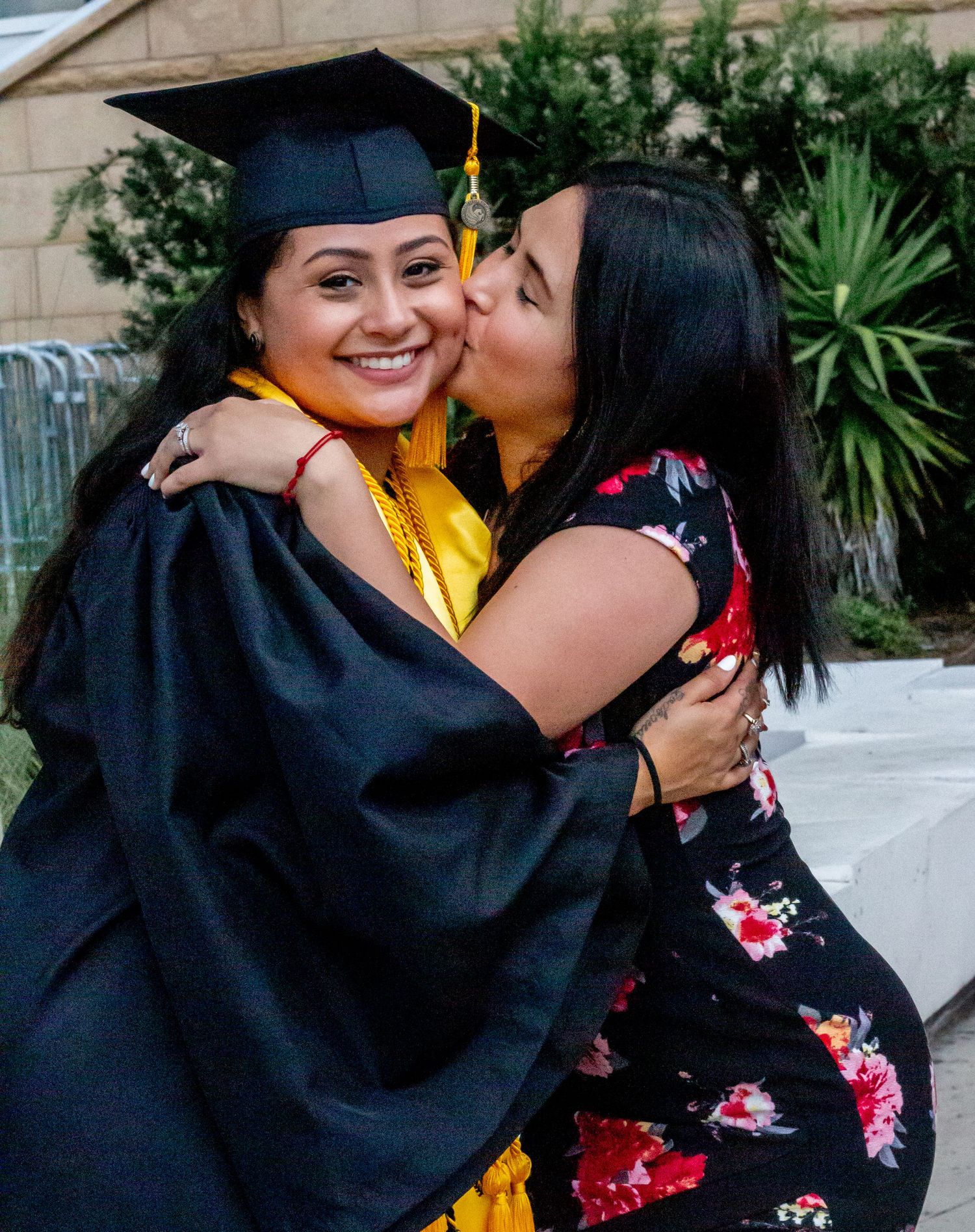 Graduation celebration with affectionate poses and black robes with gold stoles.