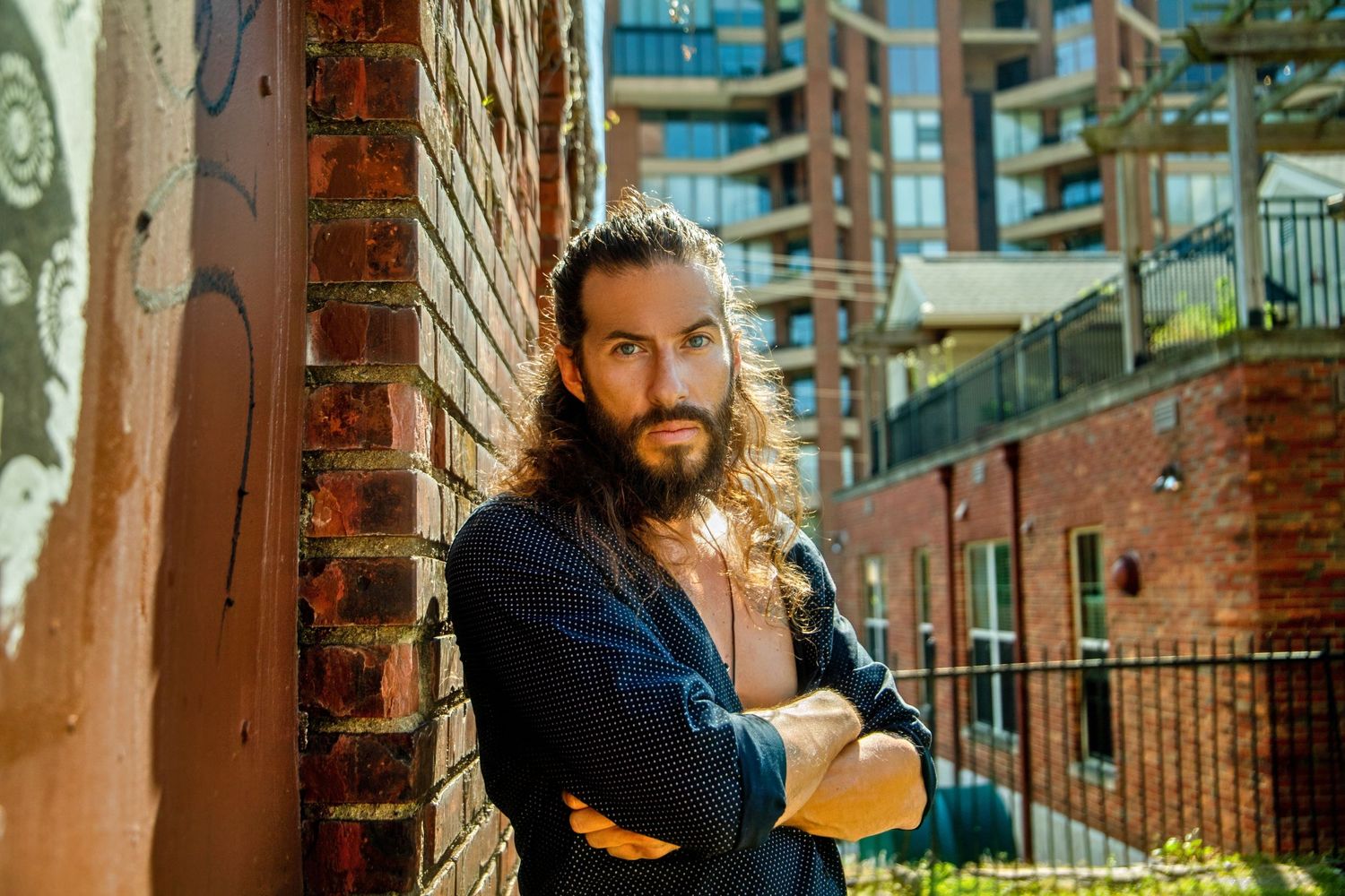 Urban rooftop portrait against city skyline and brick architecture.