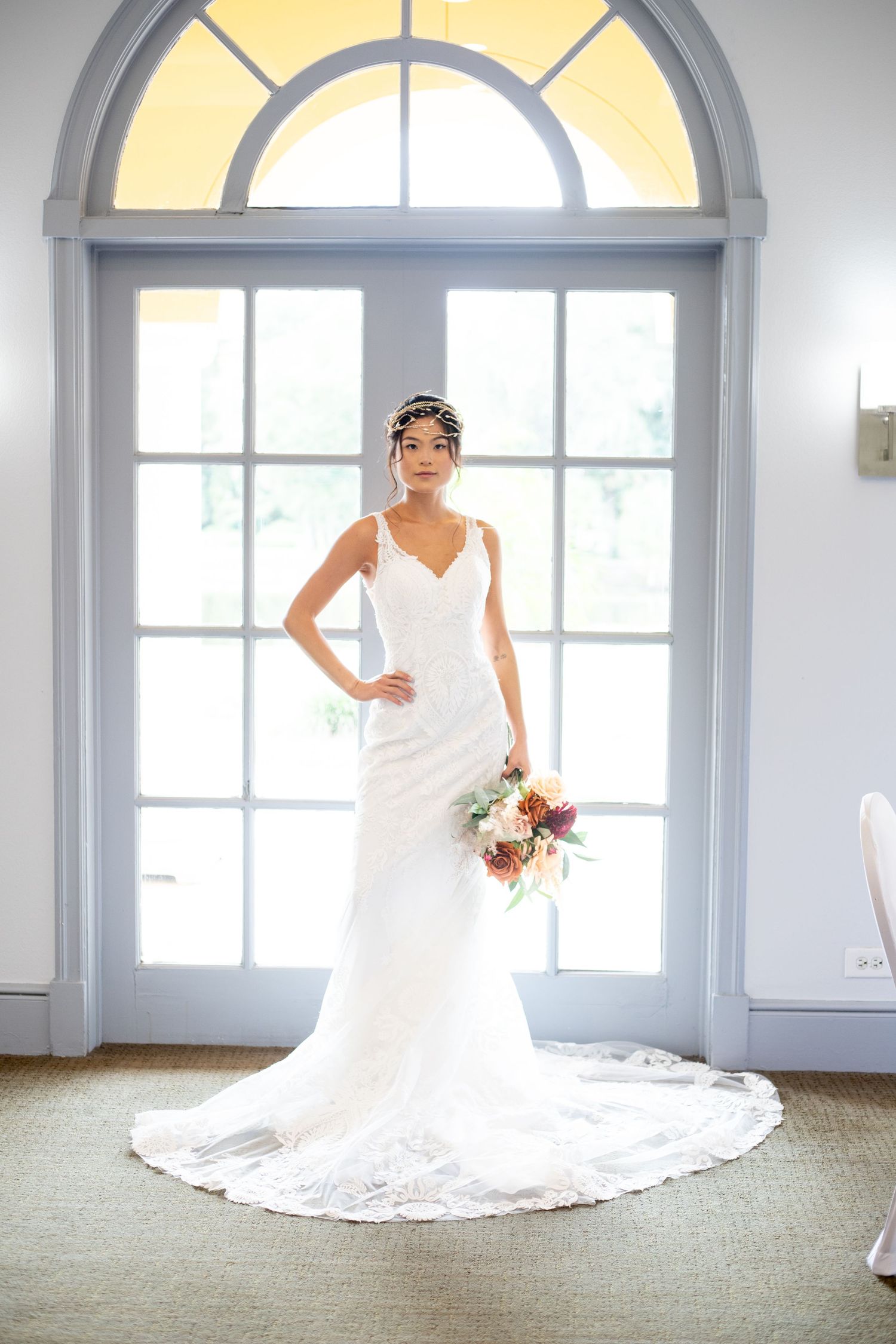 Elegant bridal poses in a bright room with arched windows and long train.