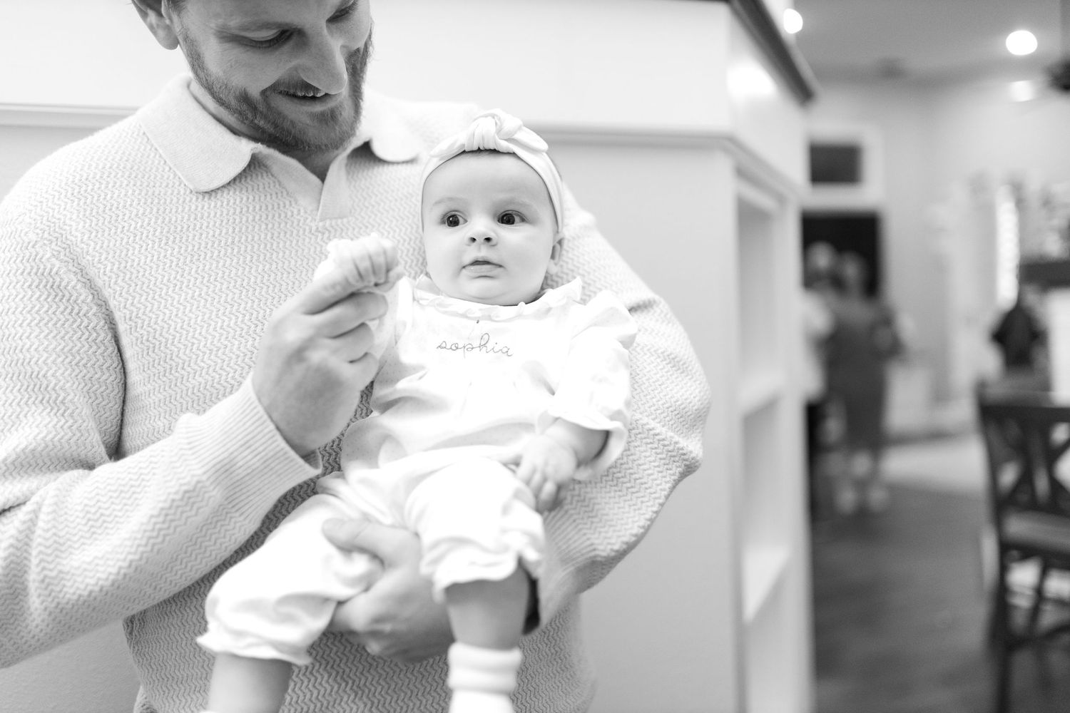 Black and white candid photos showing tender moments with a baby in white clothing.