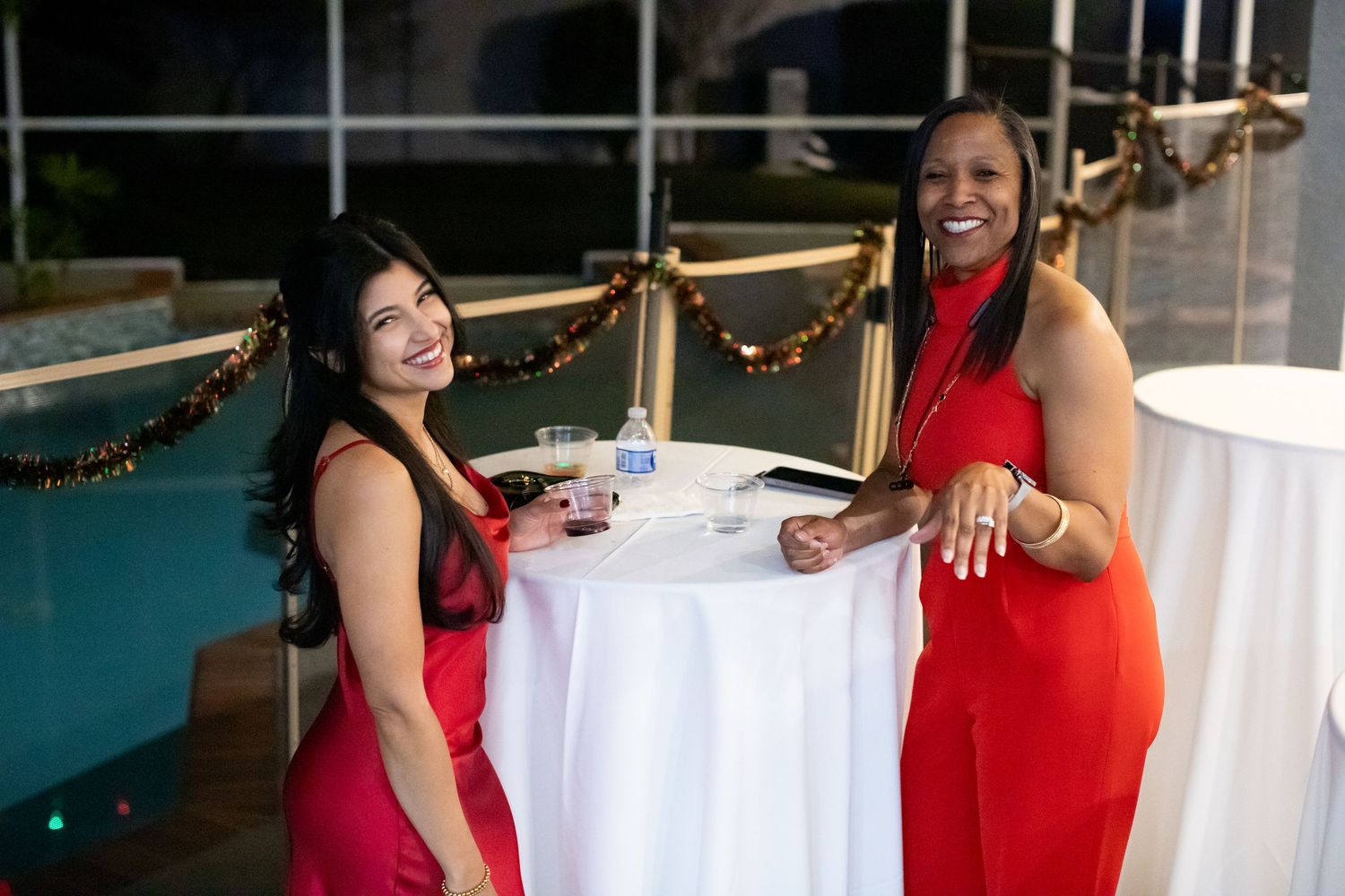 People mingling at a holiday party with decorated tables and festive atmosphere.
