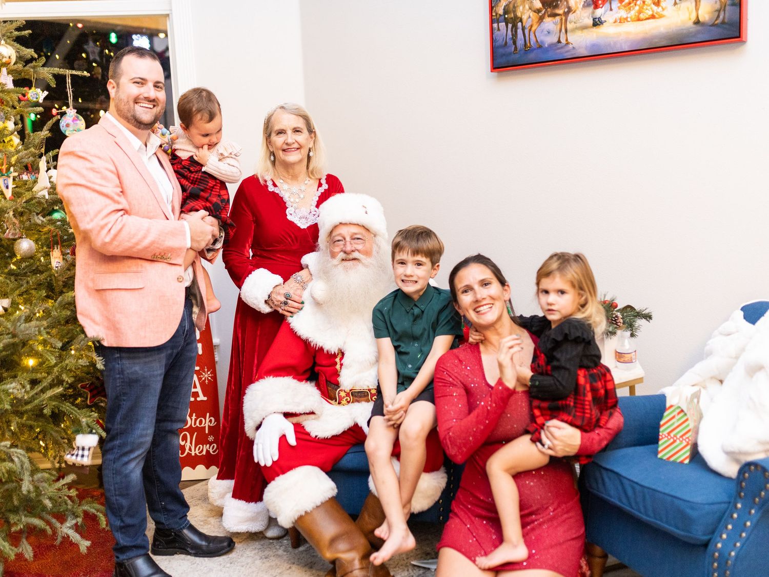 Family gathered around Santa Claus on a blue couch during Christmas photo session.