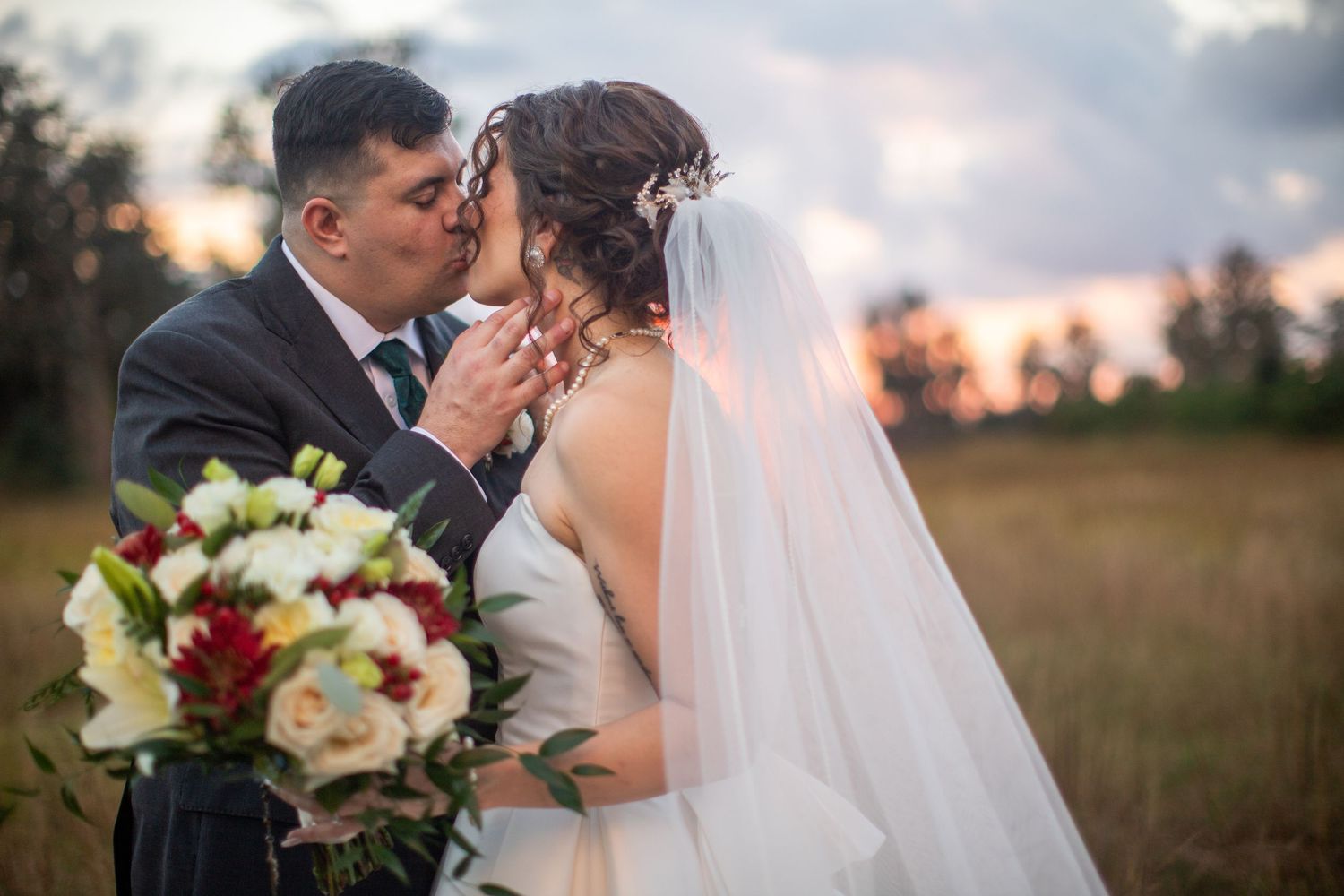 Newlyweds share an intimate moment during golden hour in an outdoor setting.