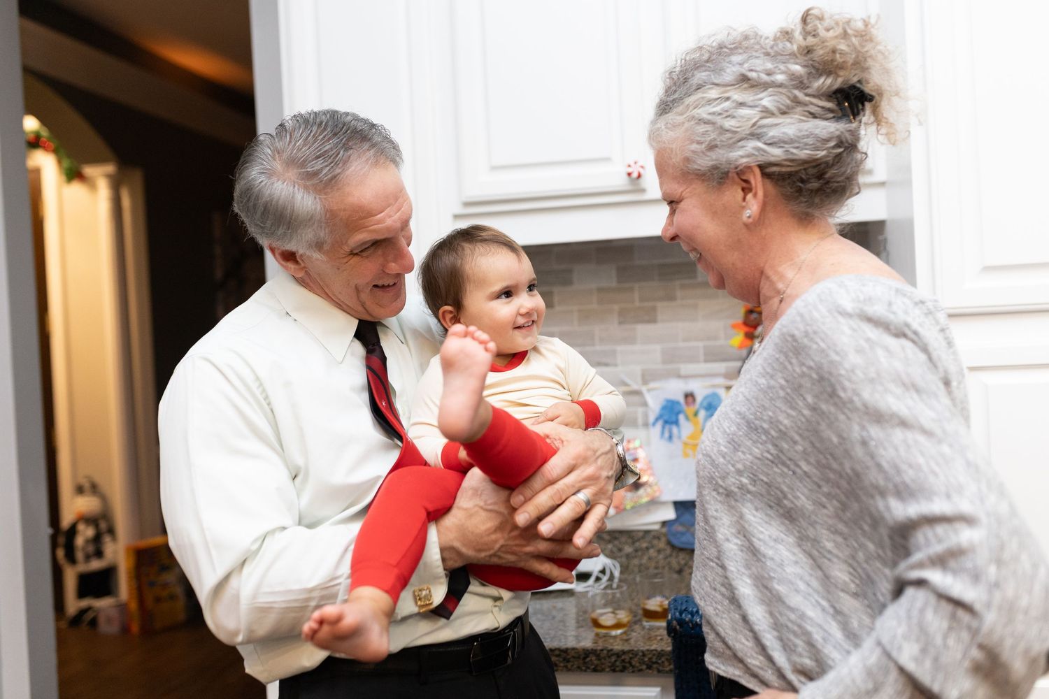 Family sharing joyful moment with baby in red outfit during holidays.