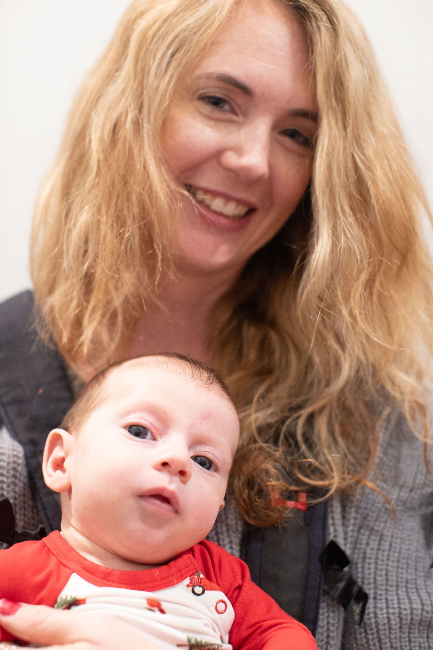 A baby in red clothing shares tender moments with caregiver.