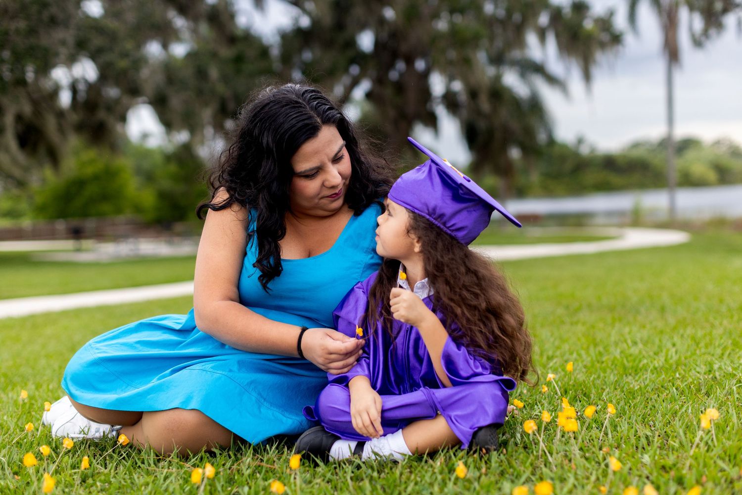 A series of playful photos showing someone in a purple graduation cap and gown laying in green grass.
