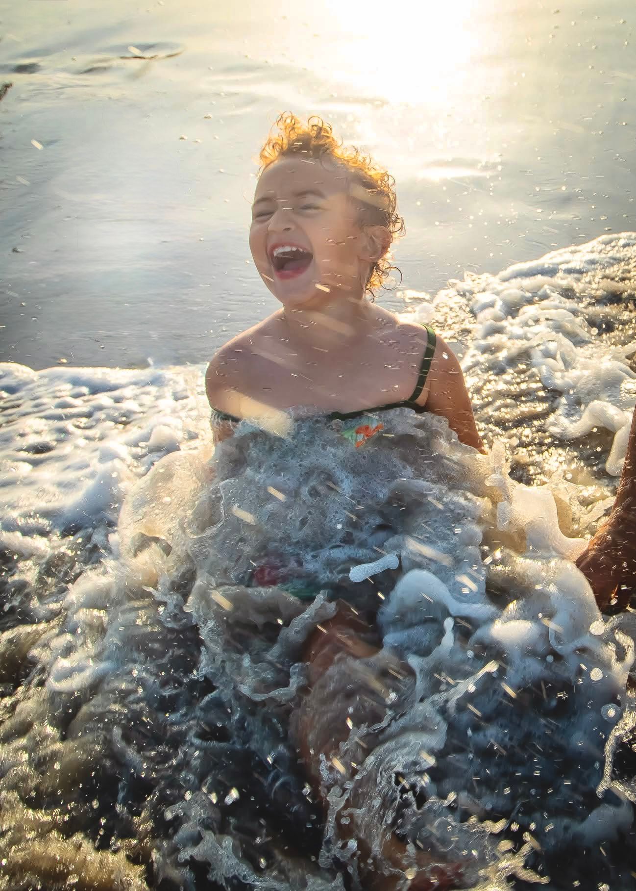 Joyful moment captured as ocean waves splash and create sea foam during sunset.