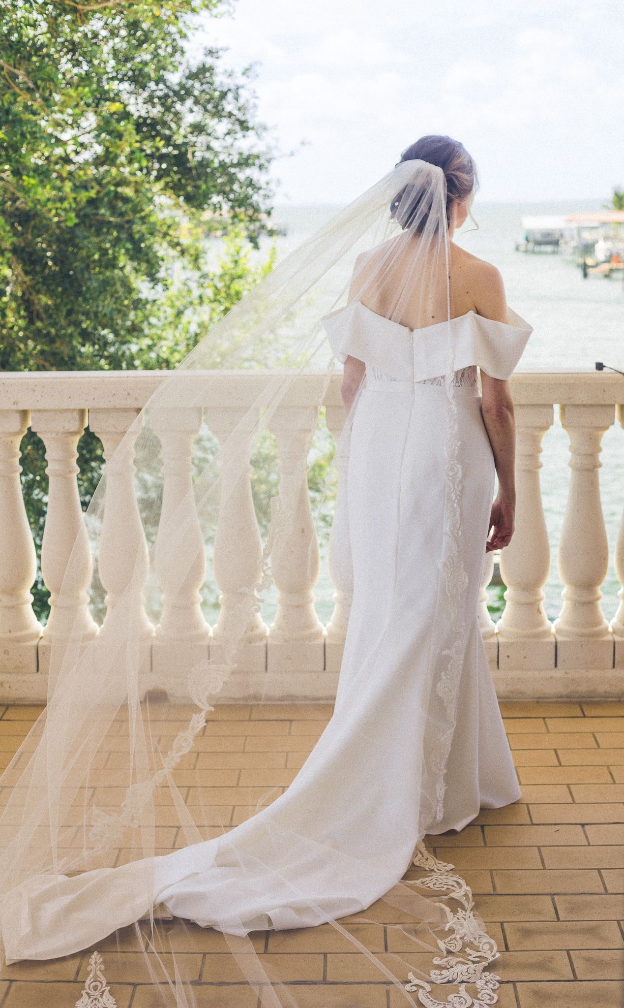Elegant bridal gown with cathedral train displayed on stone balustrade terrace.