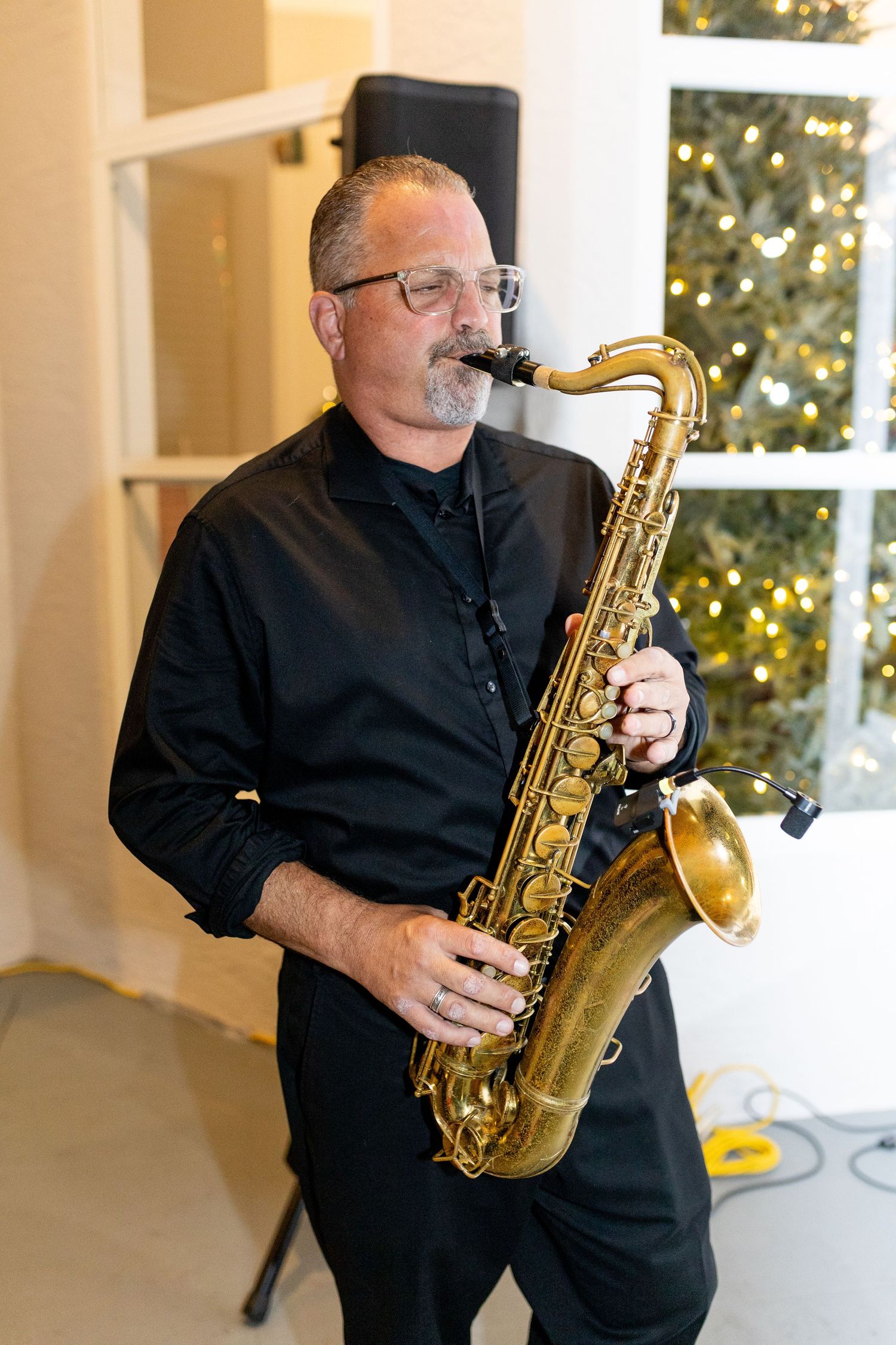 A saxophone player in black attire performs on a bright porch with multiple angles shown.