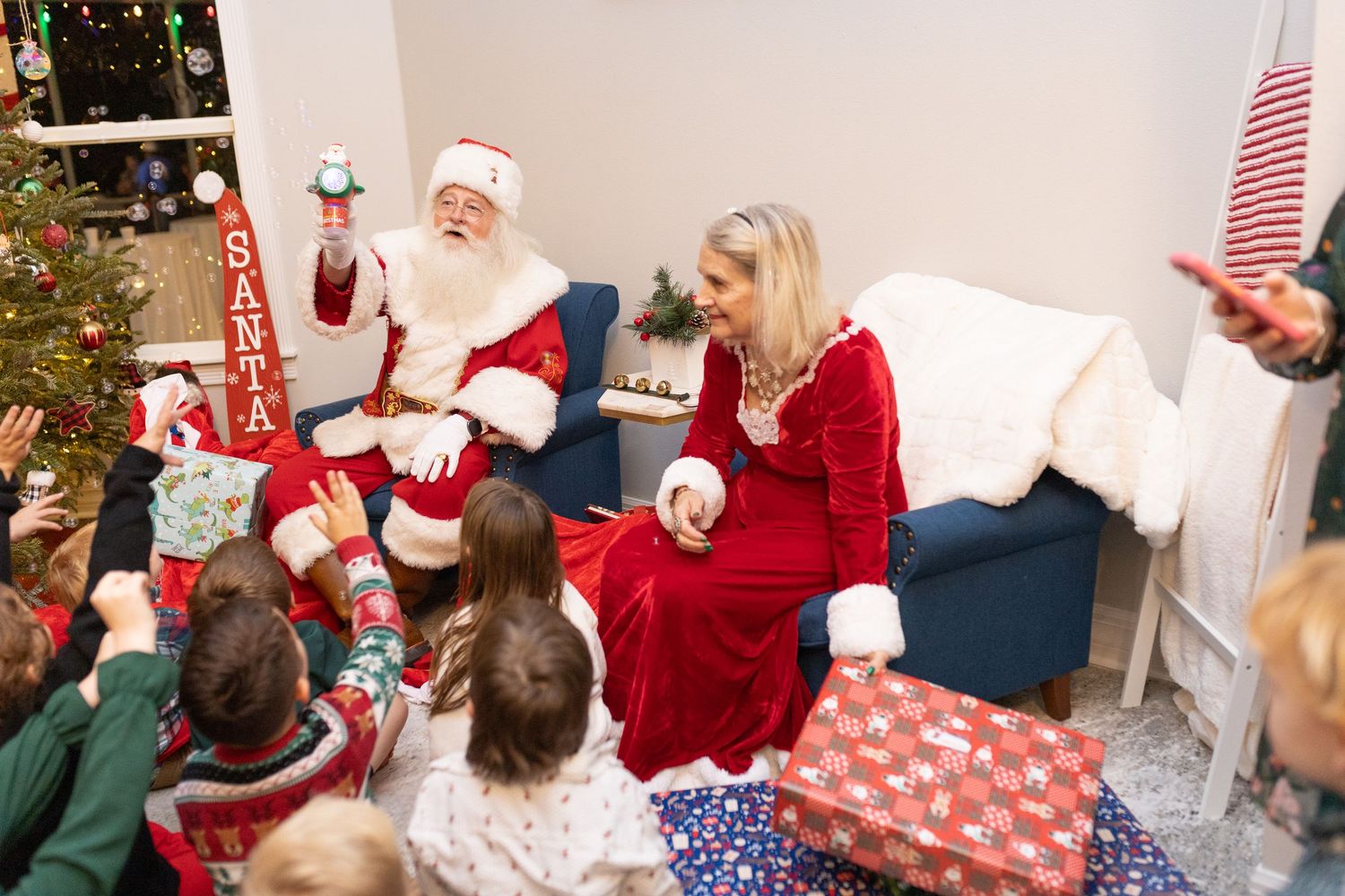 Children gather around Christmas tree for holiday gift exchange.