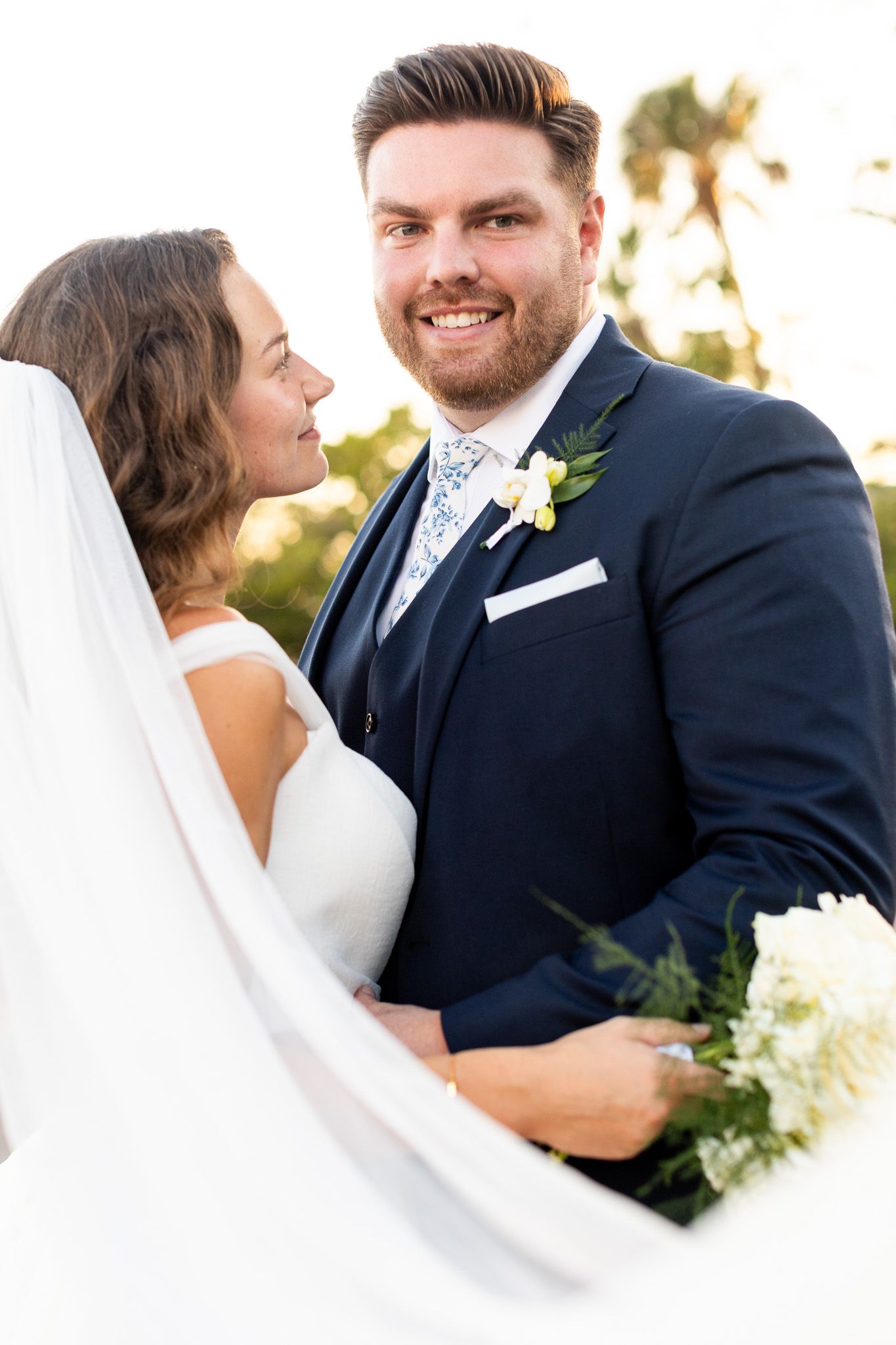 Joyful wedding portrait outdoors with white floral boutonniere.