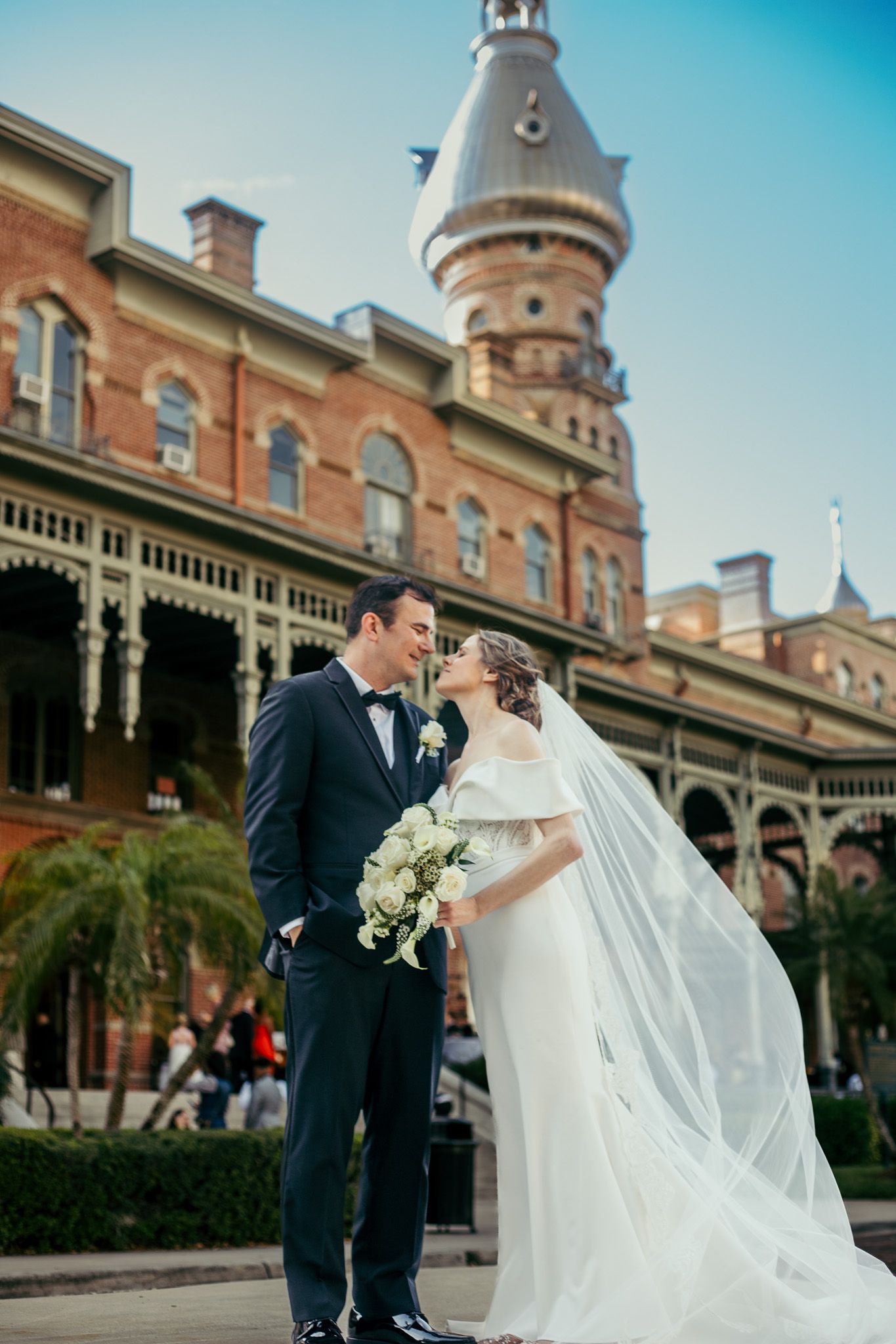 Wedding portraits captured in front of historic brick building with ornate architecture.