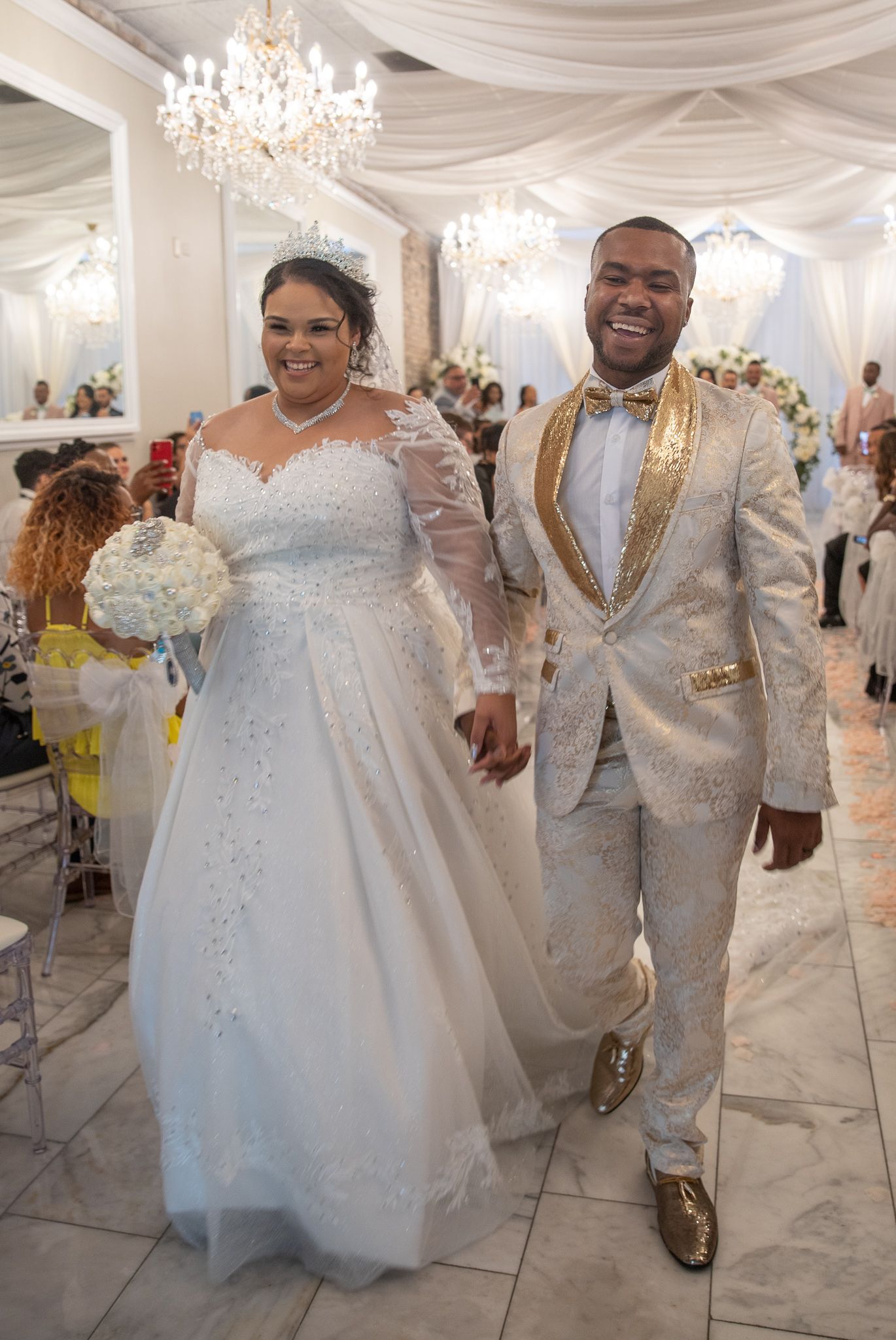 Wedding celebration in white decorated ballroom with crystal chandeliers and elegant attire.