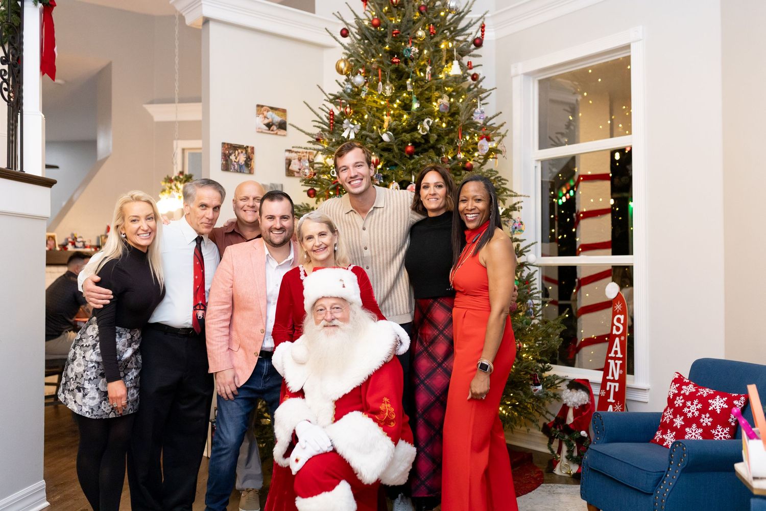 Holiday celebration with decorated Christmas tree and guests mingling in bright living room.