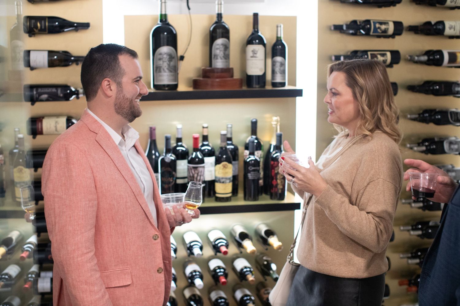 Couple browsing wine bottles in a rustic cellar with wooden shelving.