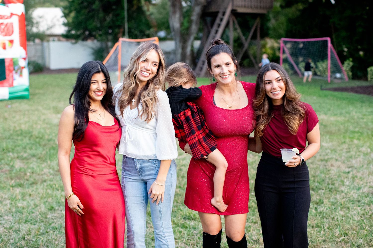 Friends posing together on grass wearing coordinated red and casual outfits.