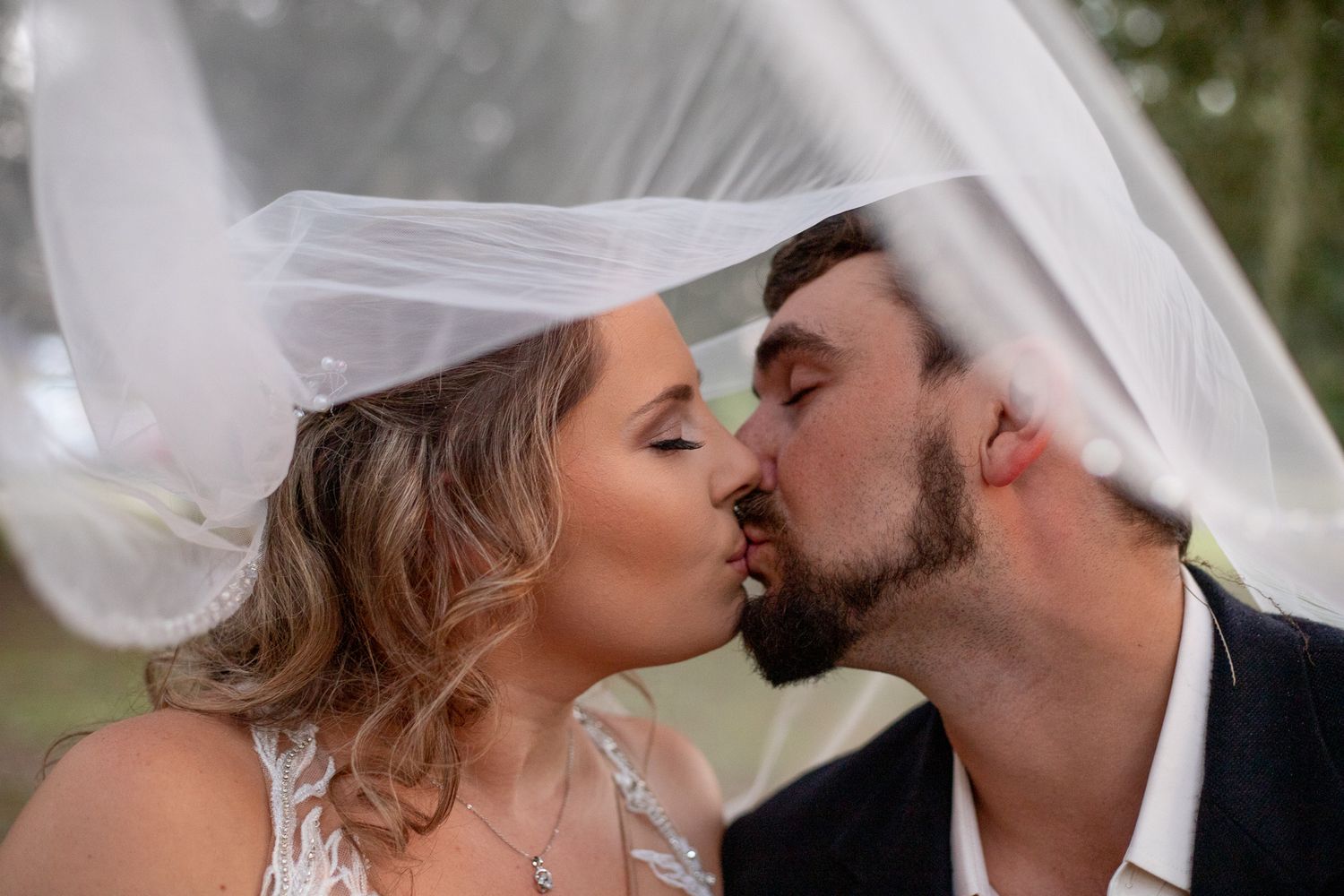 Intimate wedding kiss captured during outdoor photo session.