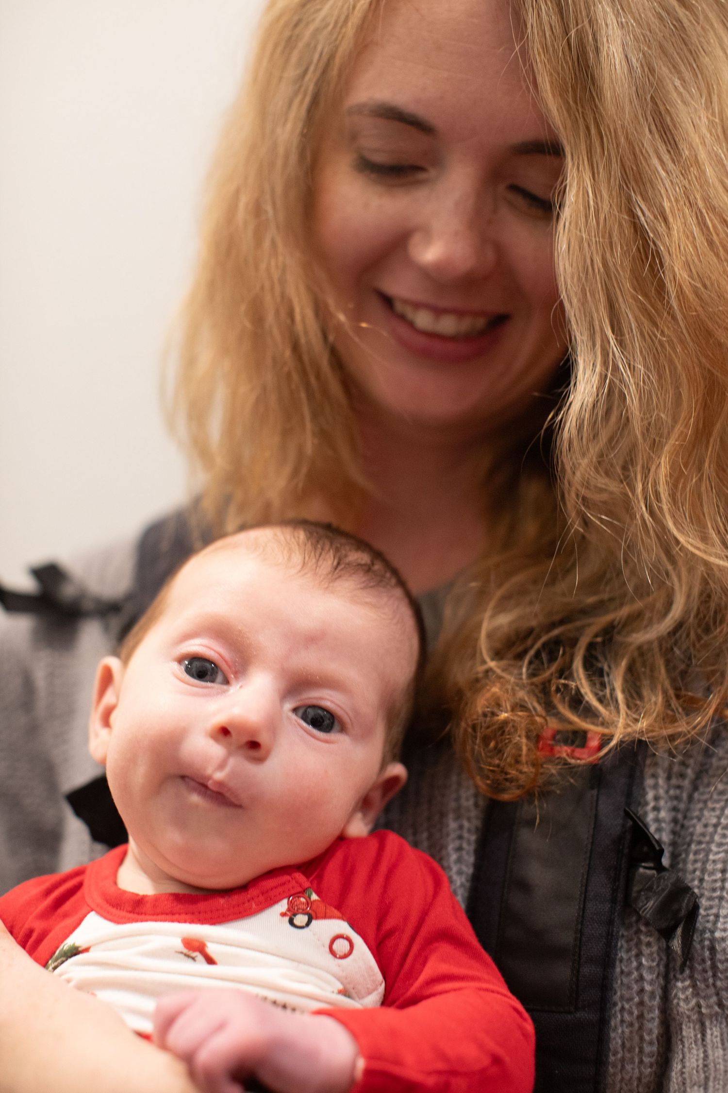 An infant in red clothing shares sweet interactions with caregiver.