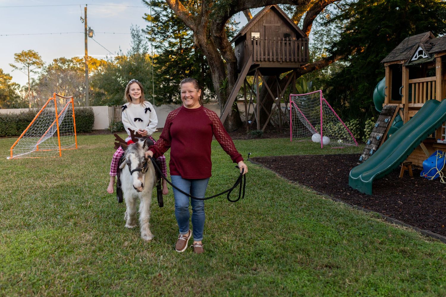 Dog and person walking together in a backyard with playground equipment.