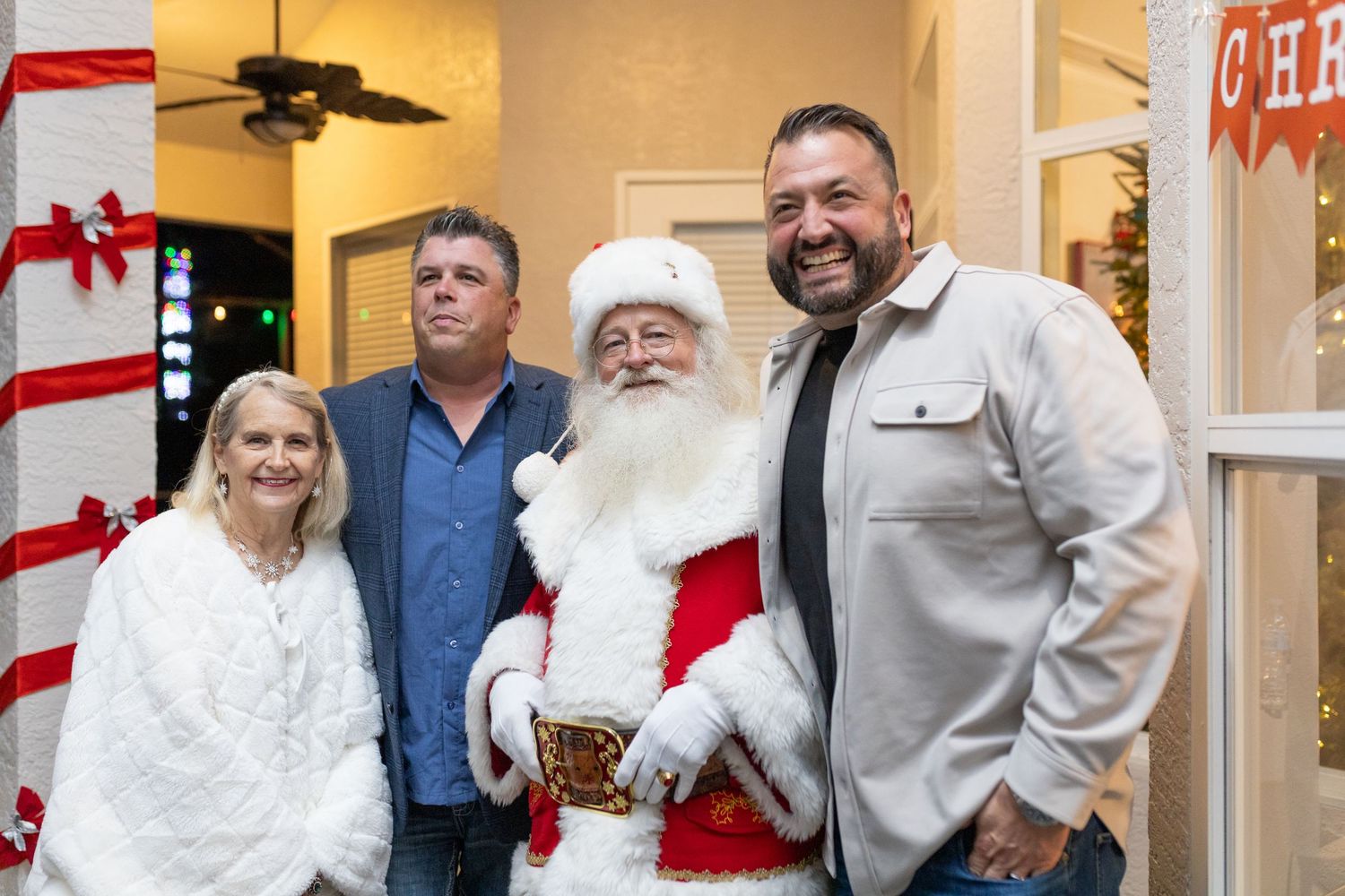 Group posing with Santa Claus in front of holiday decorations.