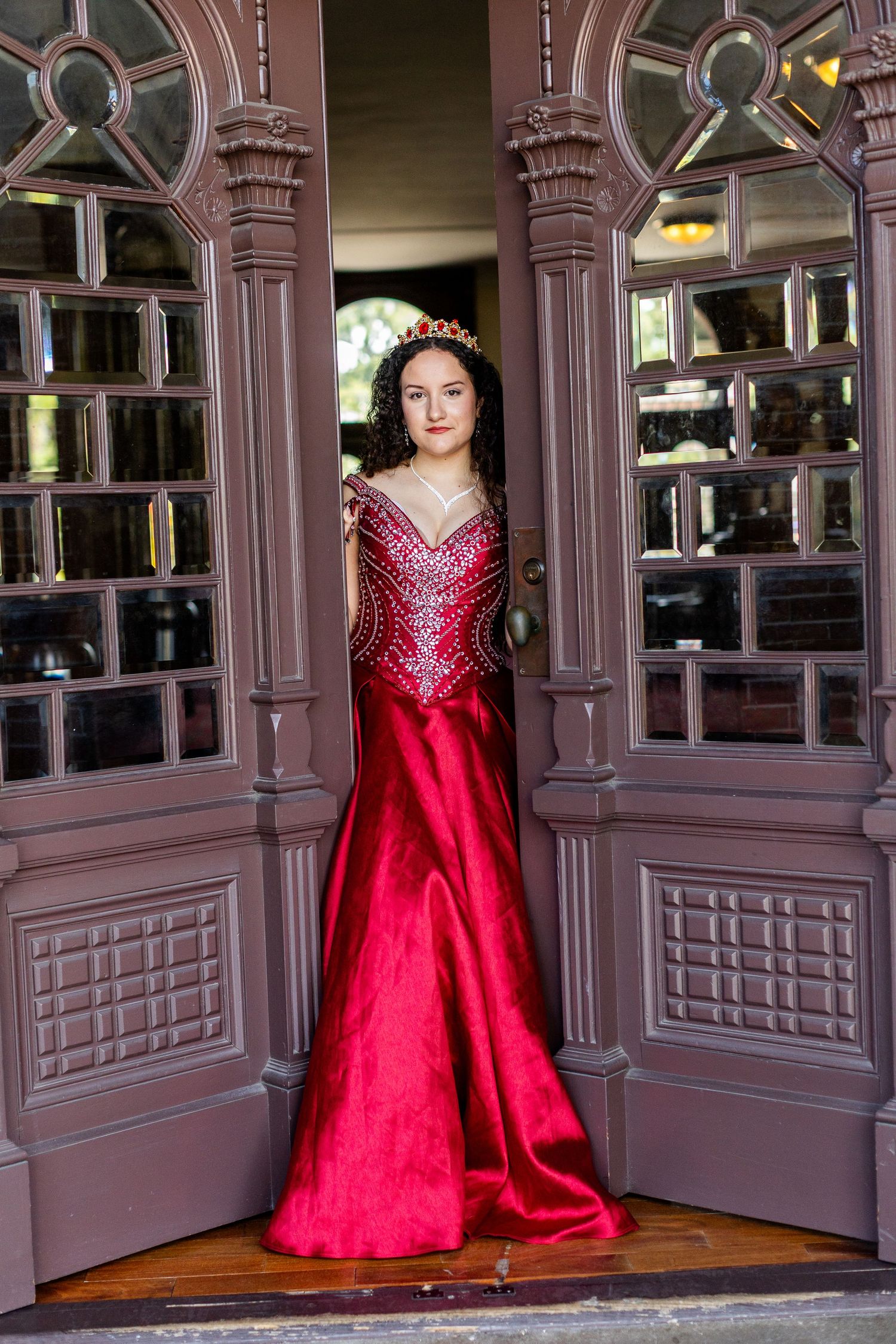 Elegant red ball gown photograph in an ornate vintage-style window alcove.