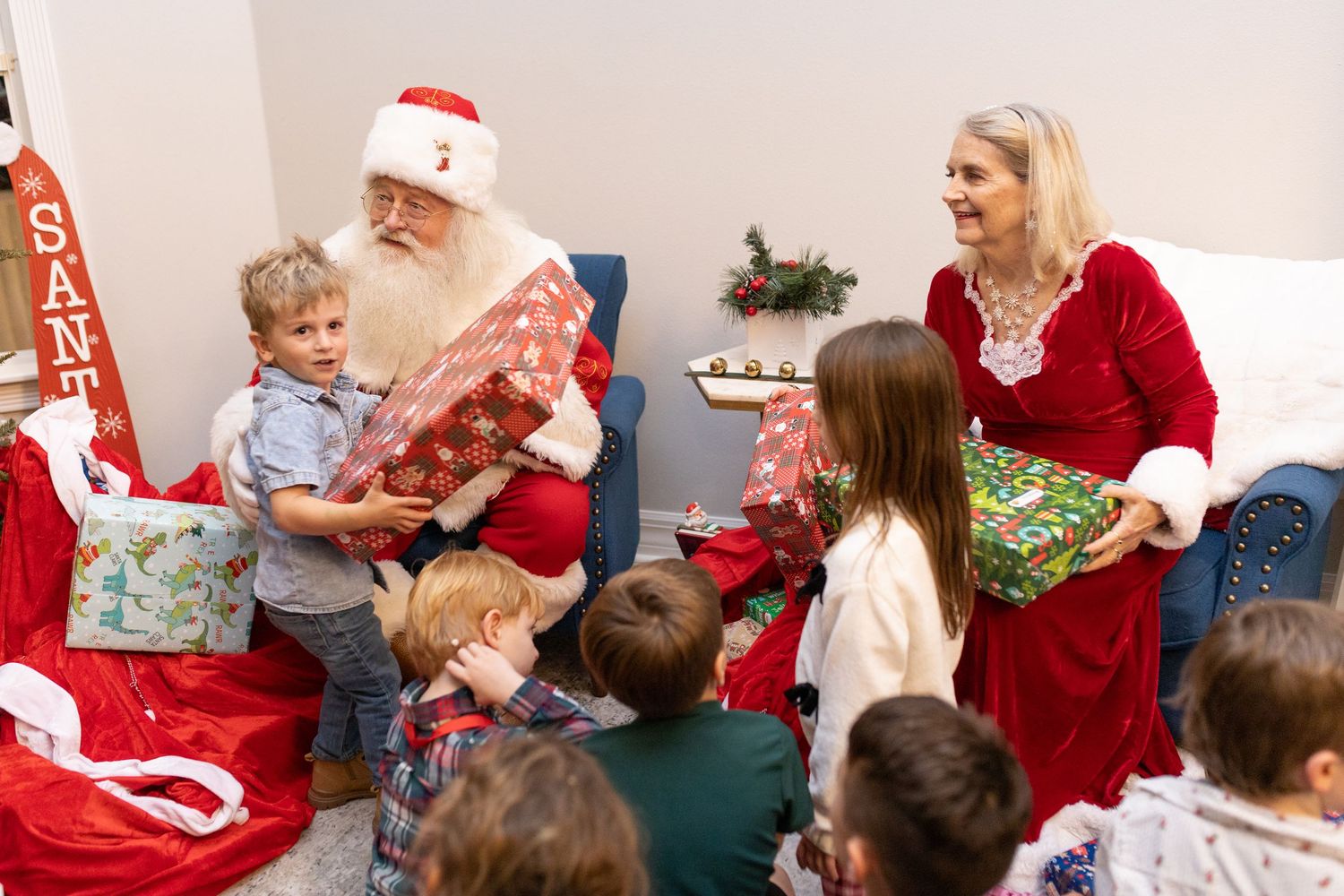 Children open Christmas presents during holiday celebration.