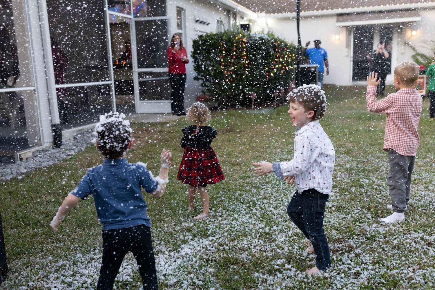 Group playing in artificial snow during outdoor winter party festivities.