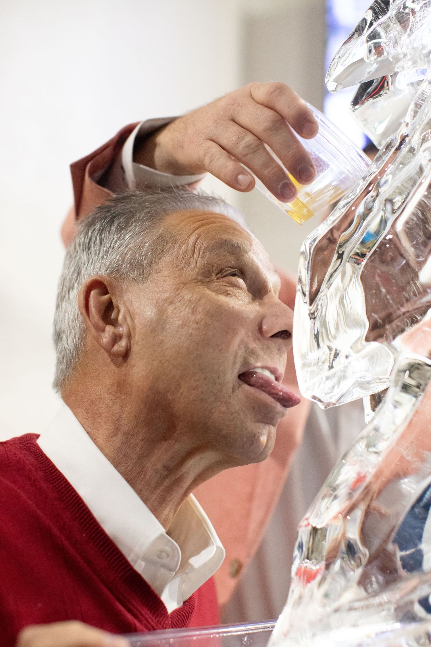 Close-up of someone drinking from an ice sculpture luge at an event.