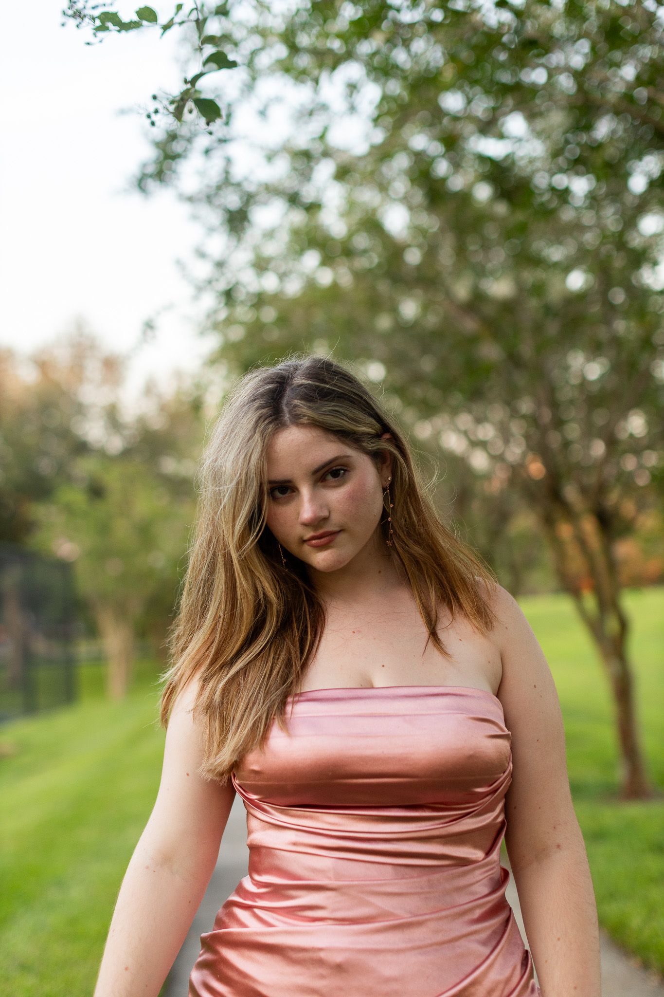Salmon pink strapless dress photographed against lush green garden background.