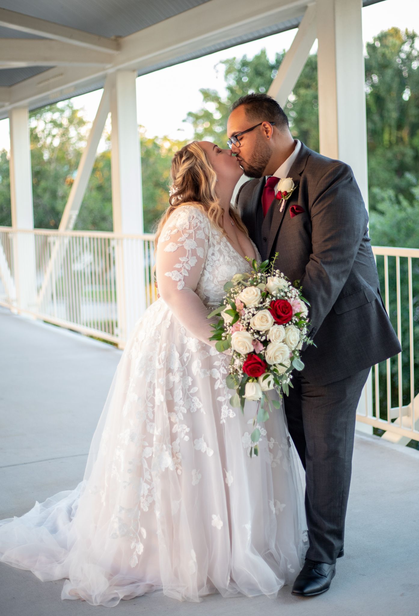 Wedding couple shares intimate moment on white covered porch during sunset.