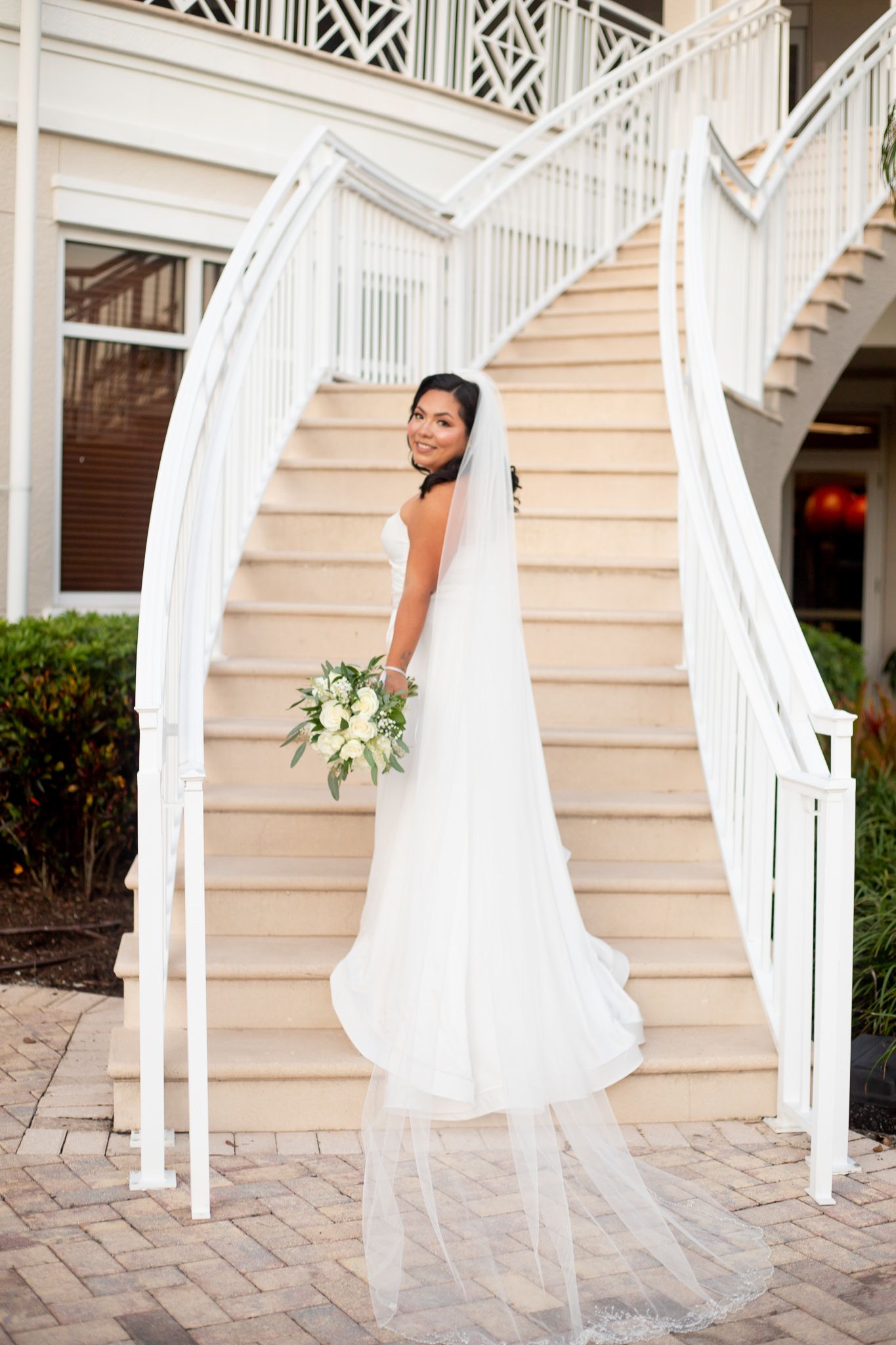 A flowing white wedding dress photographed in sections against an elegant white staircase and railing.
