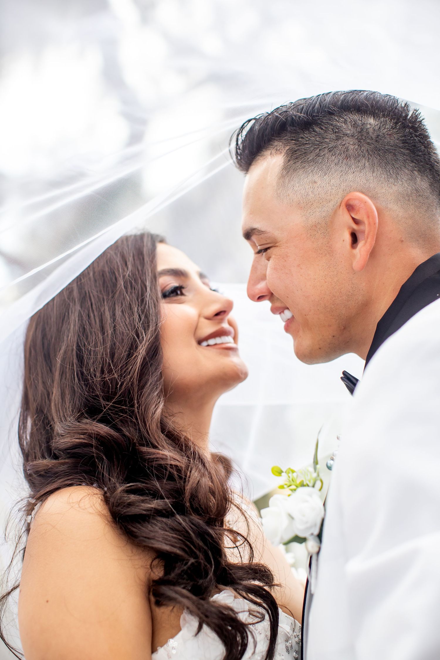 An intimate wedding portrait moment captured under a delicate white veil.