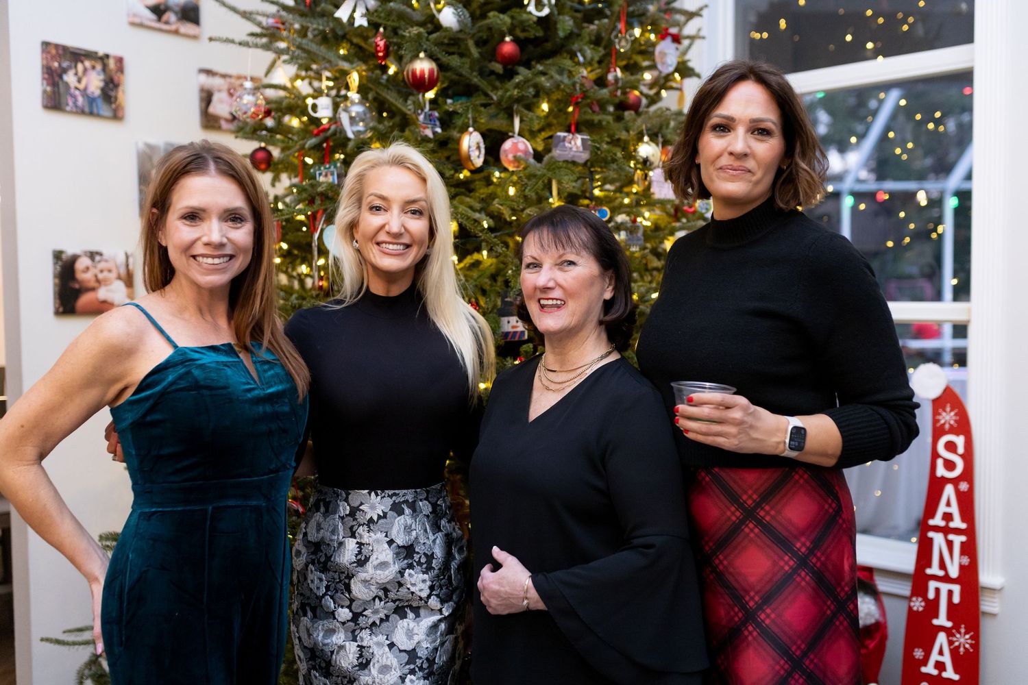Holiday gathering with friends posing in front of a decorated Christmas tree.