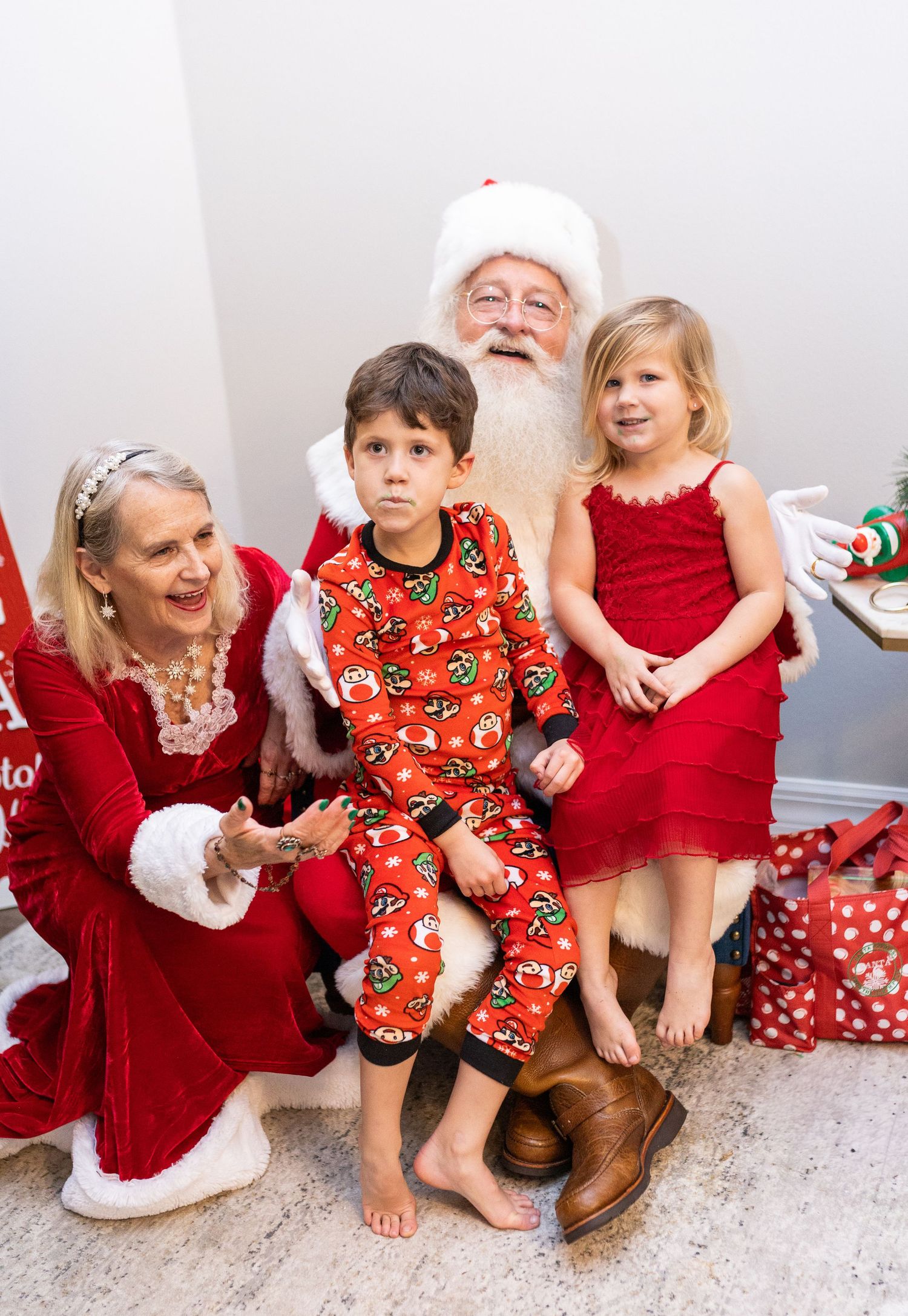 Family wearing festive red and Christmas-themed outfits sitting together during holiday photos.