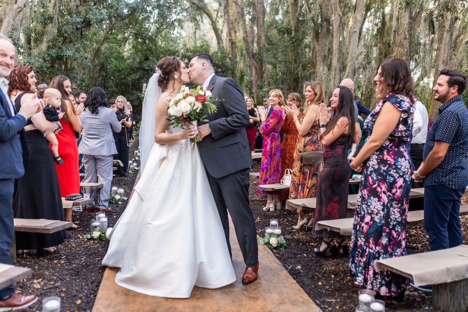 Wedding celebration under moss-draped trees with guests gathered in an outdoor setting.
