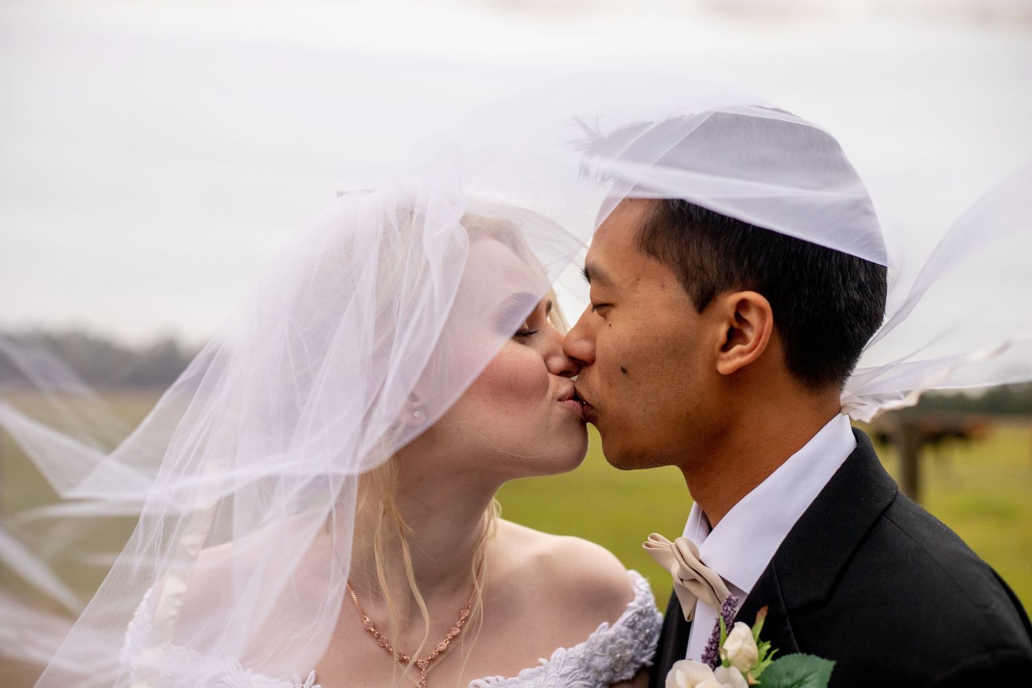 Tender wedding kiss captured in soft natural lighting.